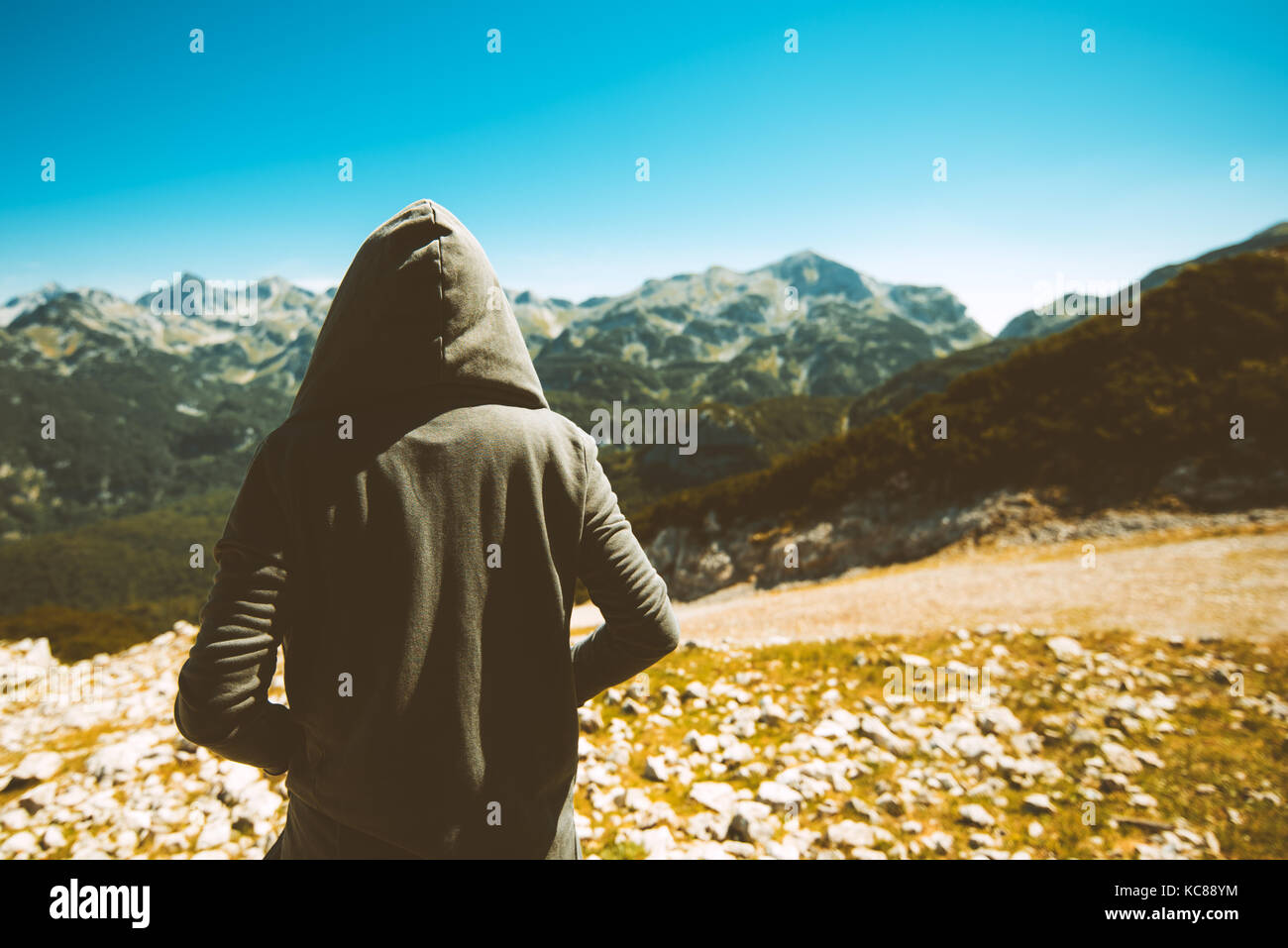 Femmina irriconoscibile la persona che sta in piedi in alta montagna viewpoint. vista posteriore del giovane adulto donna che indossa hoodie guardando a distanza su orizzonte. tonica Foto Stock