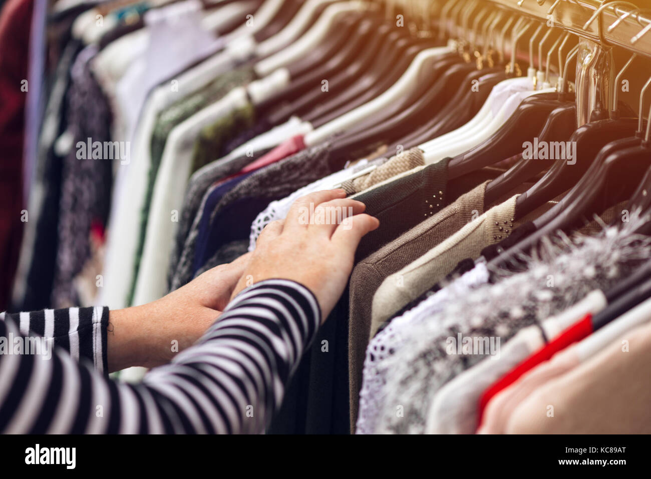 Donna navigando attraverso i vestiti di seconda mano di street market, il fuoco selettivo sui vestiti Foto Stock