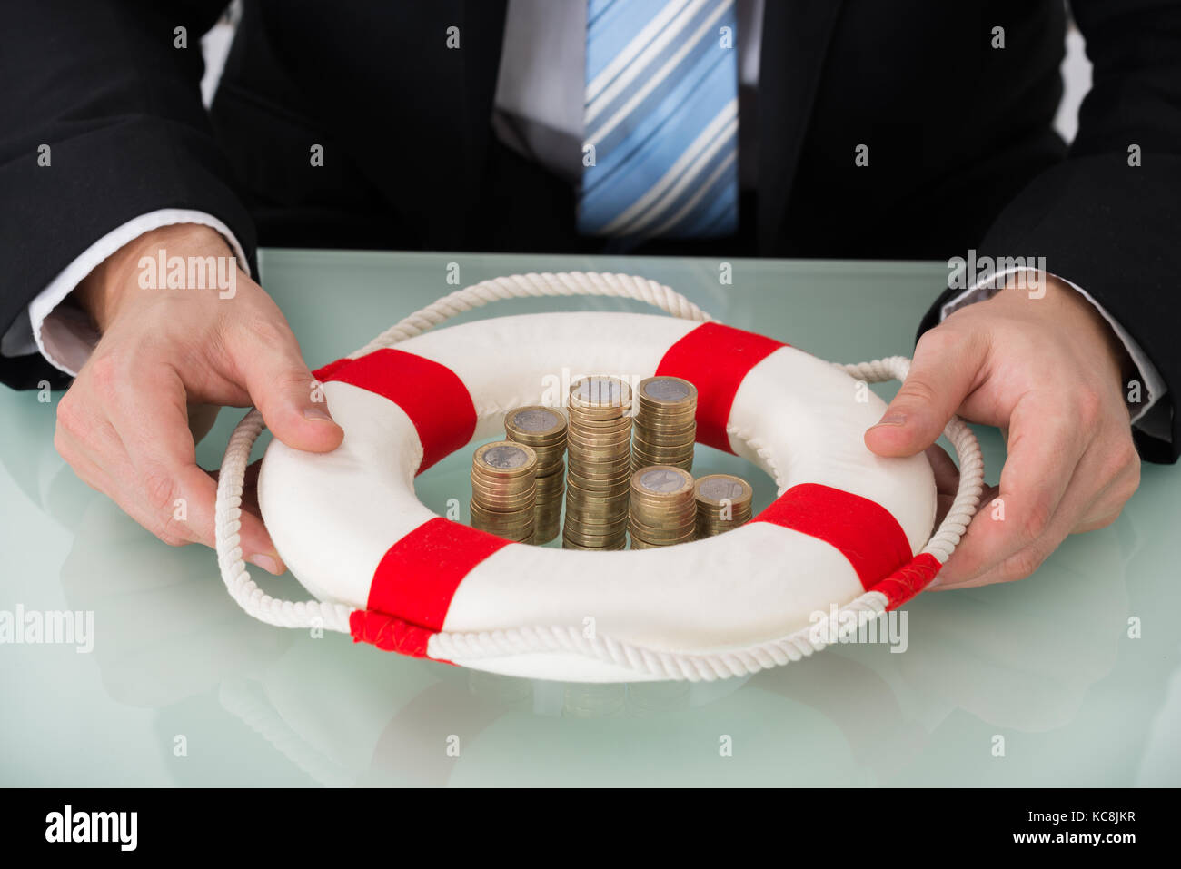 Close-up di persona in possesso di Lifebelt con monete impilate Foto Stock