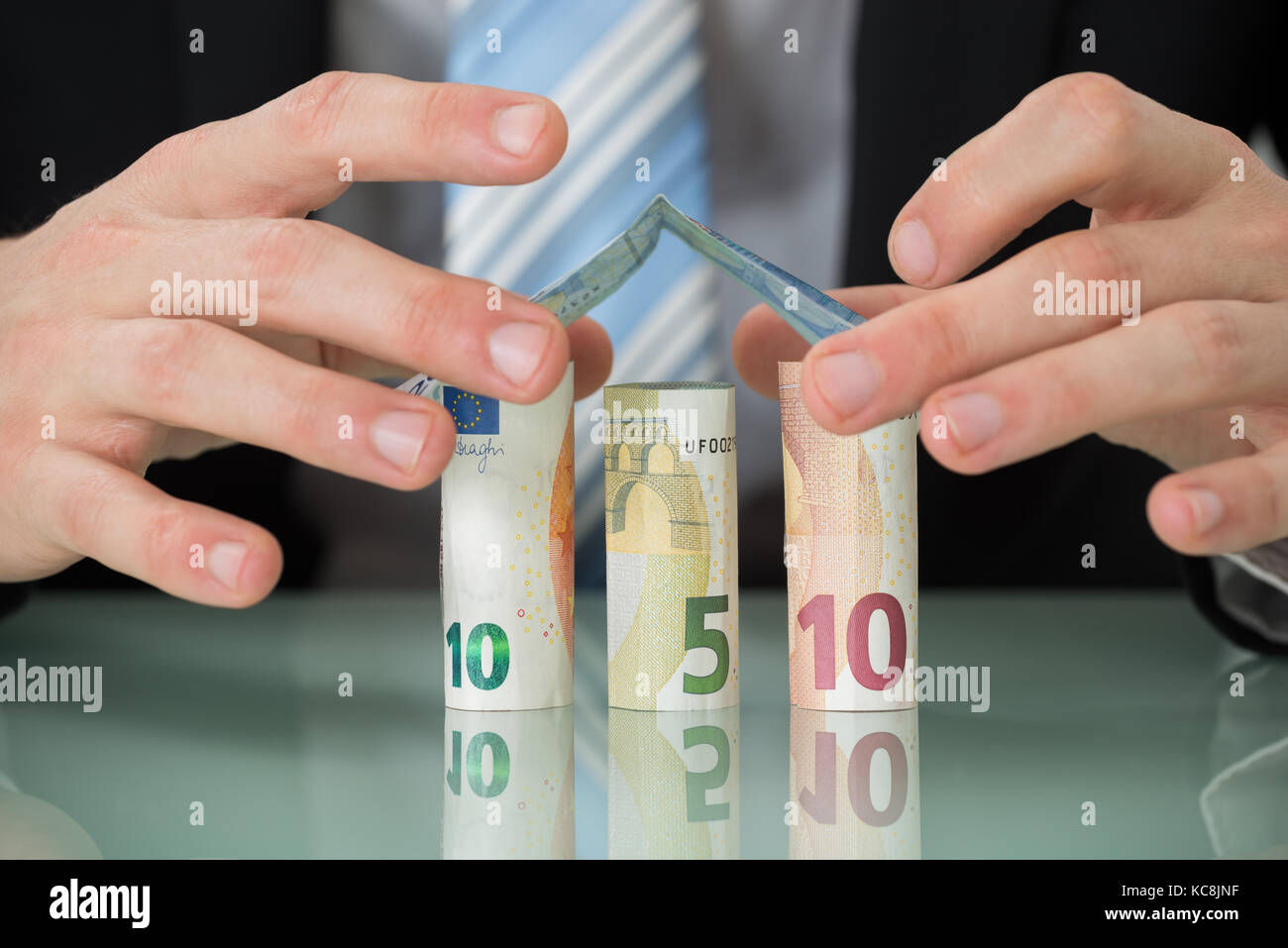 Close-up di imprenditore mano rendendo Casa di banconote in euro Foto Stock