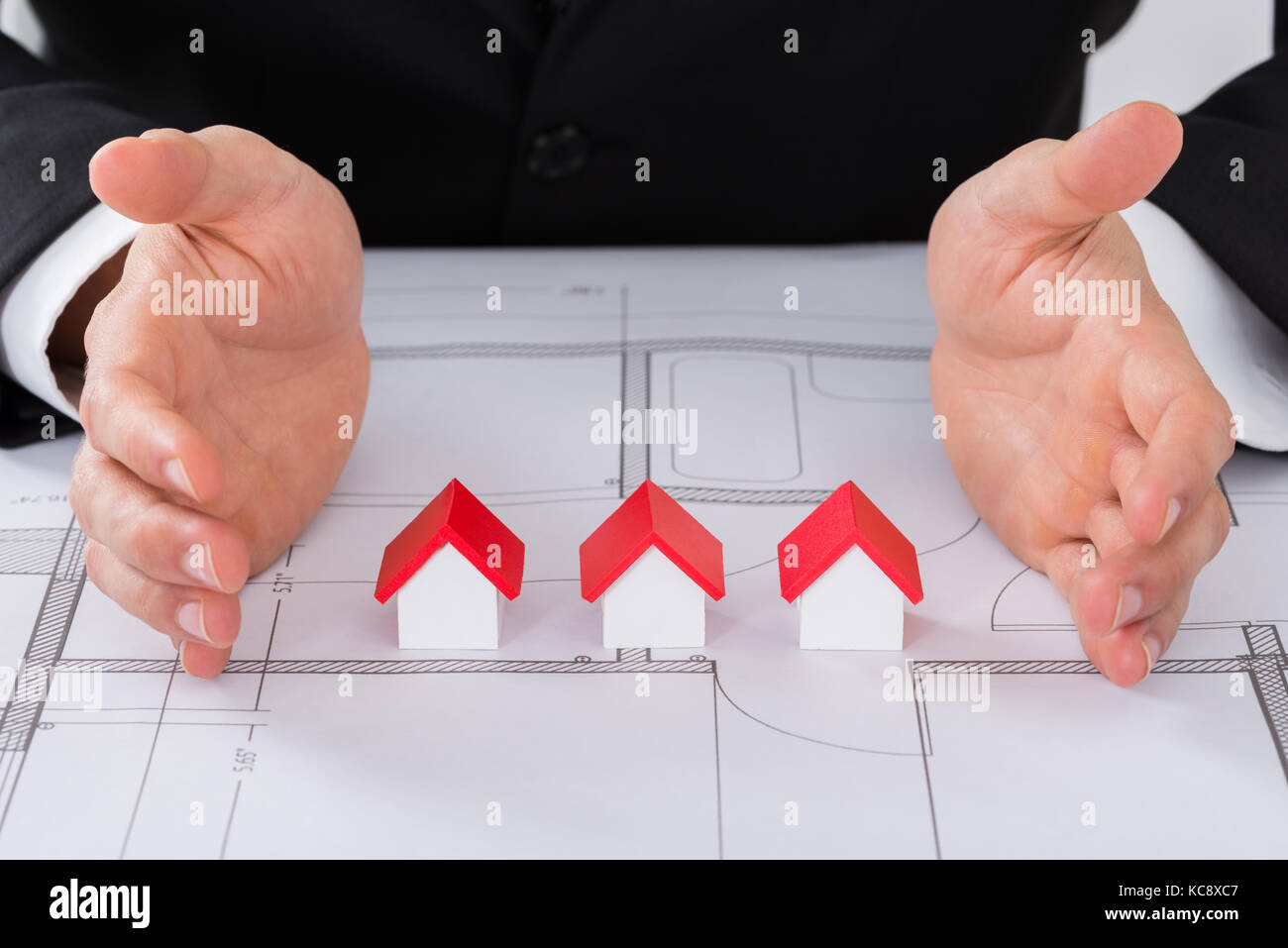 Close-up di architetto maschio lato la protezione di diversa dimensione dei modelli della casa il blueprint Foto Stock