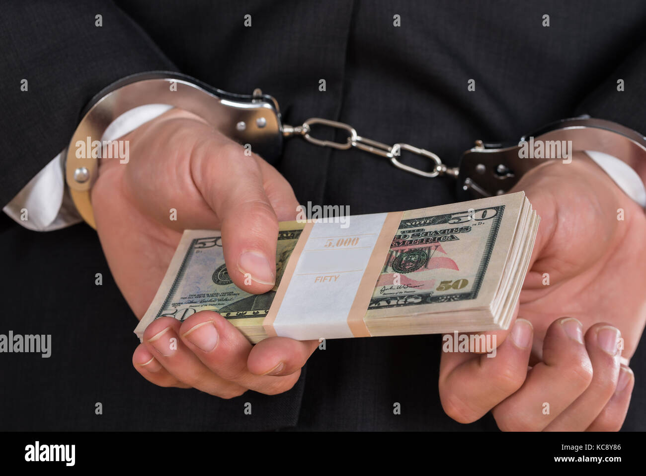 Close-up di imprenditore in manette Holding di dollari per corrompere Foto Stock
