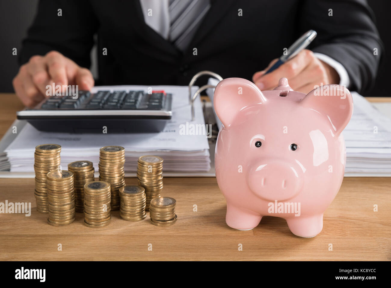 Imprenditore calcolo fattura con Piggybank e monete a scrivania da ufficio Foto Stock