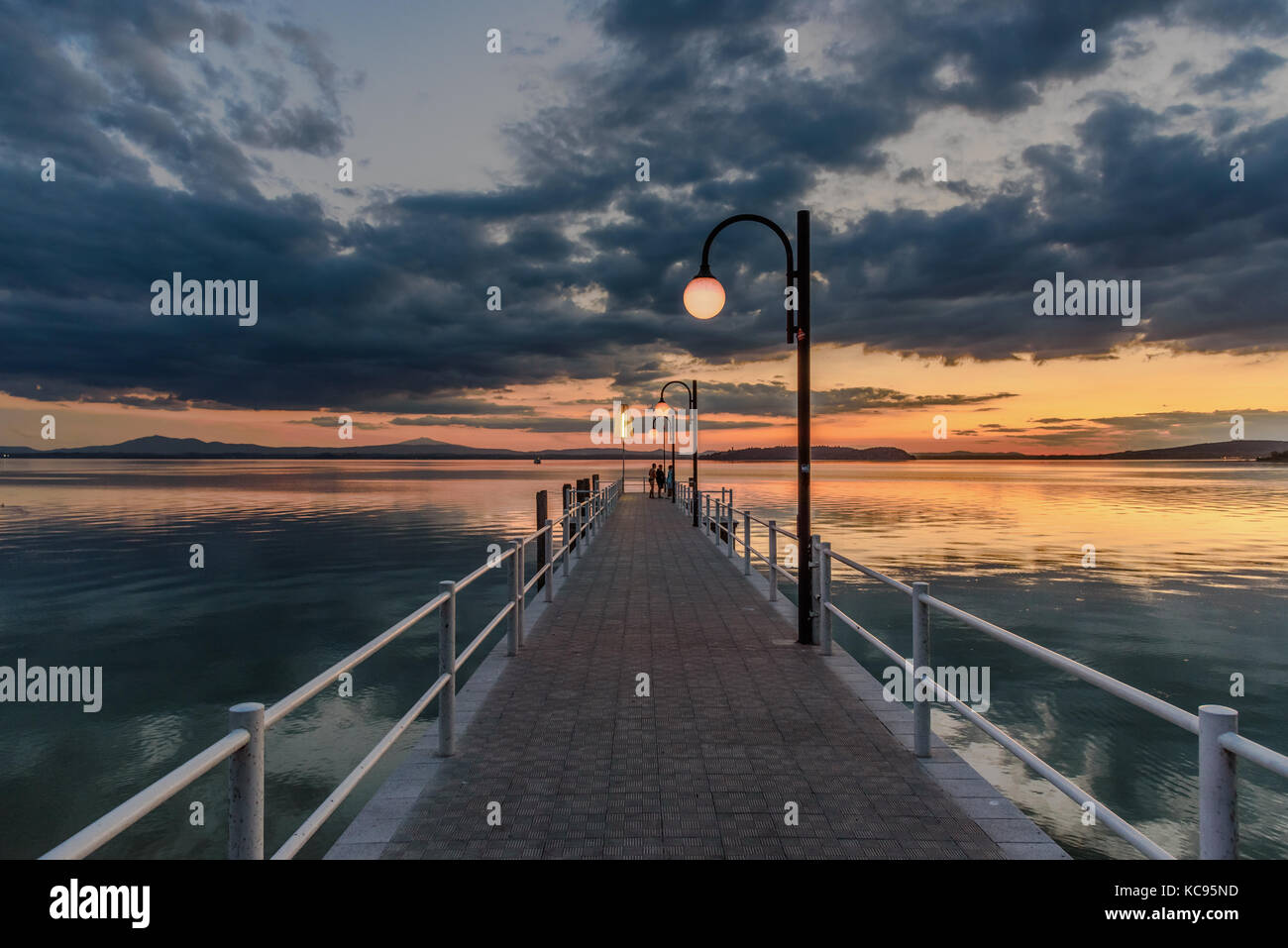 Persone su un molo al tramonto a Passignano sul Trasimeno, Umbria, Italia Foto Stock