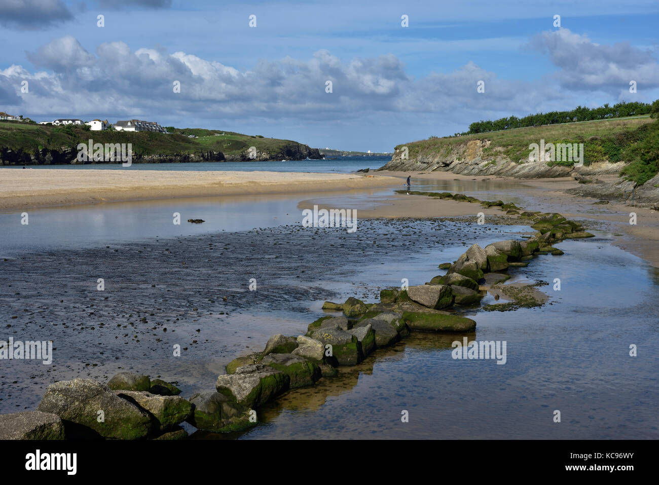 La spiaggia di Porth, Newquay, alta marea con un lontano vacanziere solitario alla fine di una linea di pietre miliari. Foto Stock