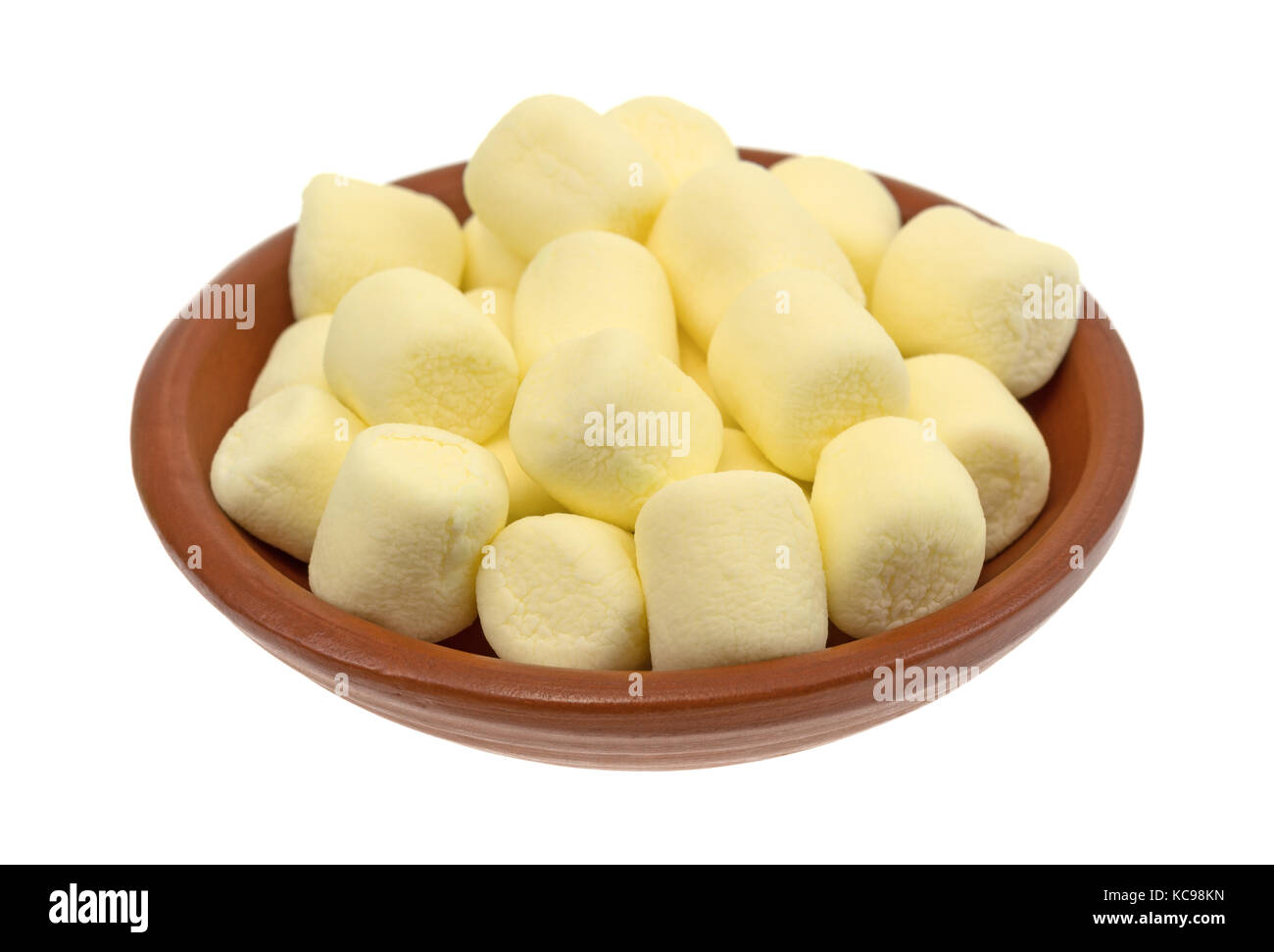 Una piccola rossa argilla ciotola riempita con giallo in miniatura marshmallows isolato su uno sfondo bianco. Foto Stock