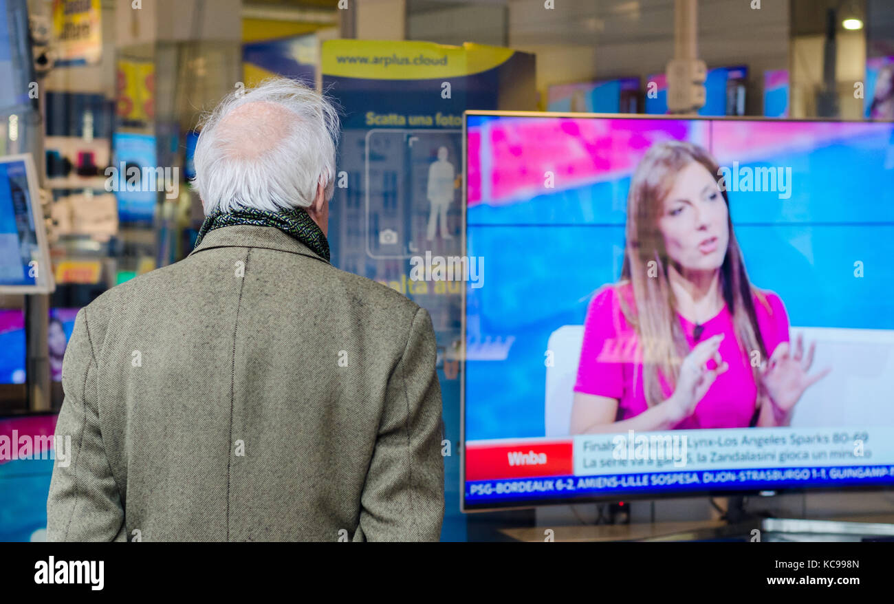 Un uomo più vecchio calvo con il dorso girato guardando una TV in mostra in un negozio Foto Stock