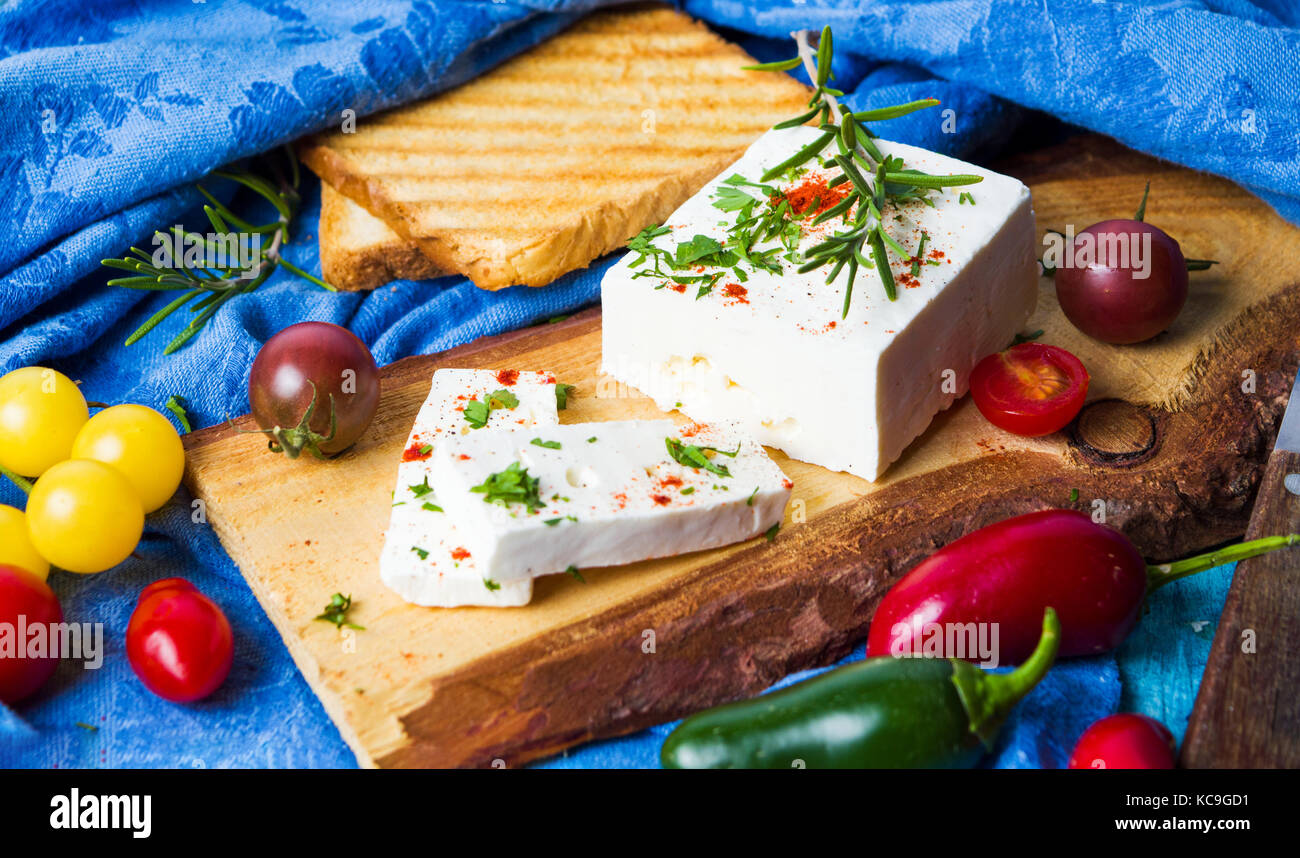 Formaggio con verdura e pane tostato naturale sul pannello di legno Foto Stock