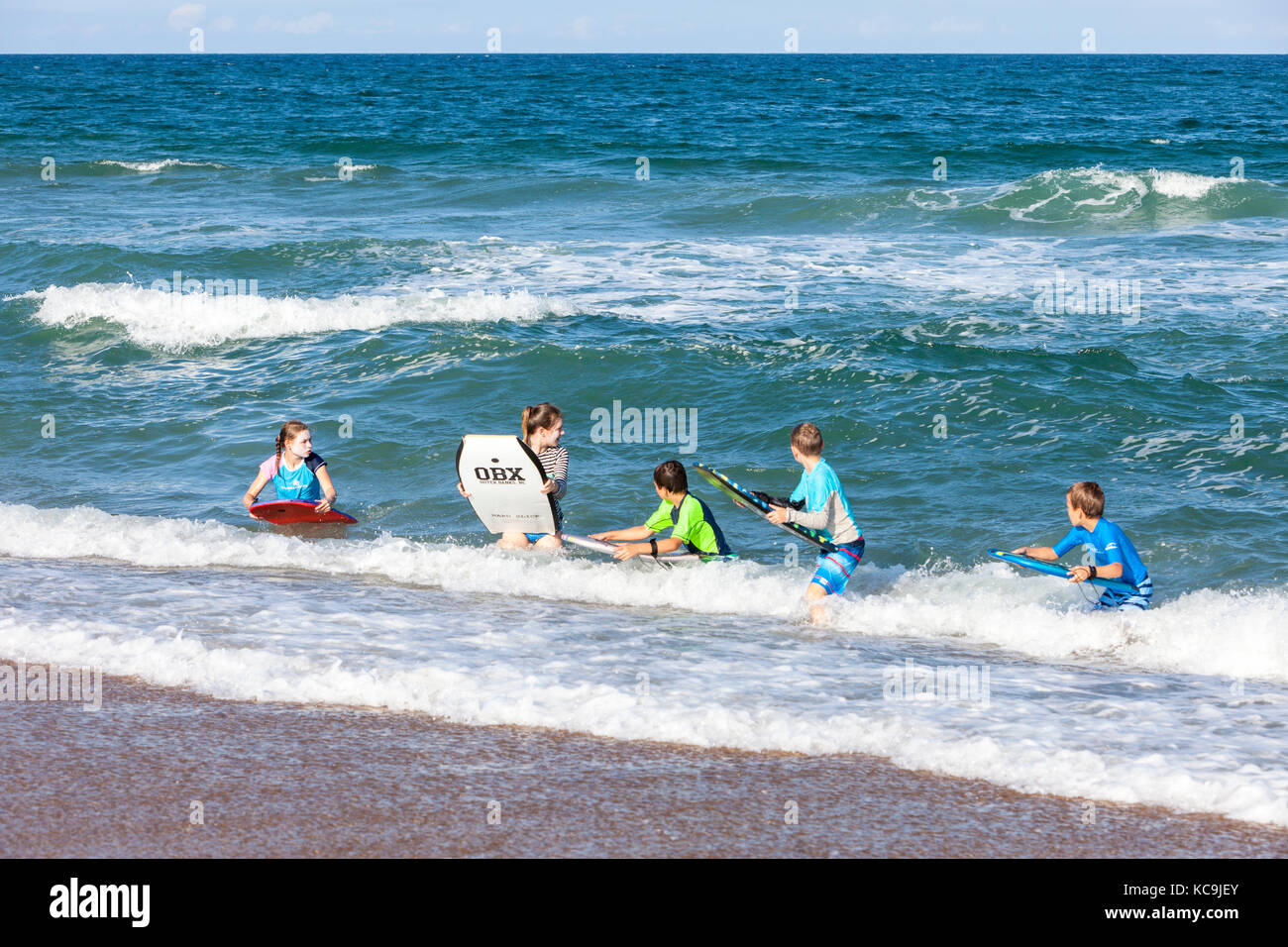 Avon, Outer Banks, North Carolina, Stati Uniti d'America. Bambini che giocano su tavole boogie in Atlantico Surf. Foto Stock