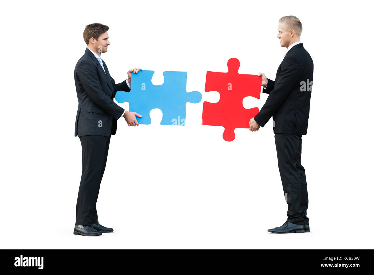 Due imprenditori risolvendo puzzle mentre in piedi su sfondo bianco Foto Stock
