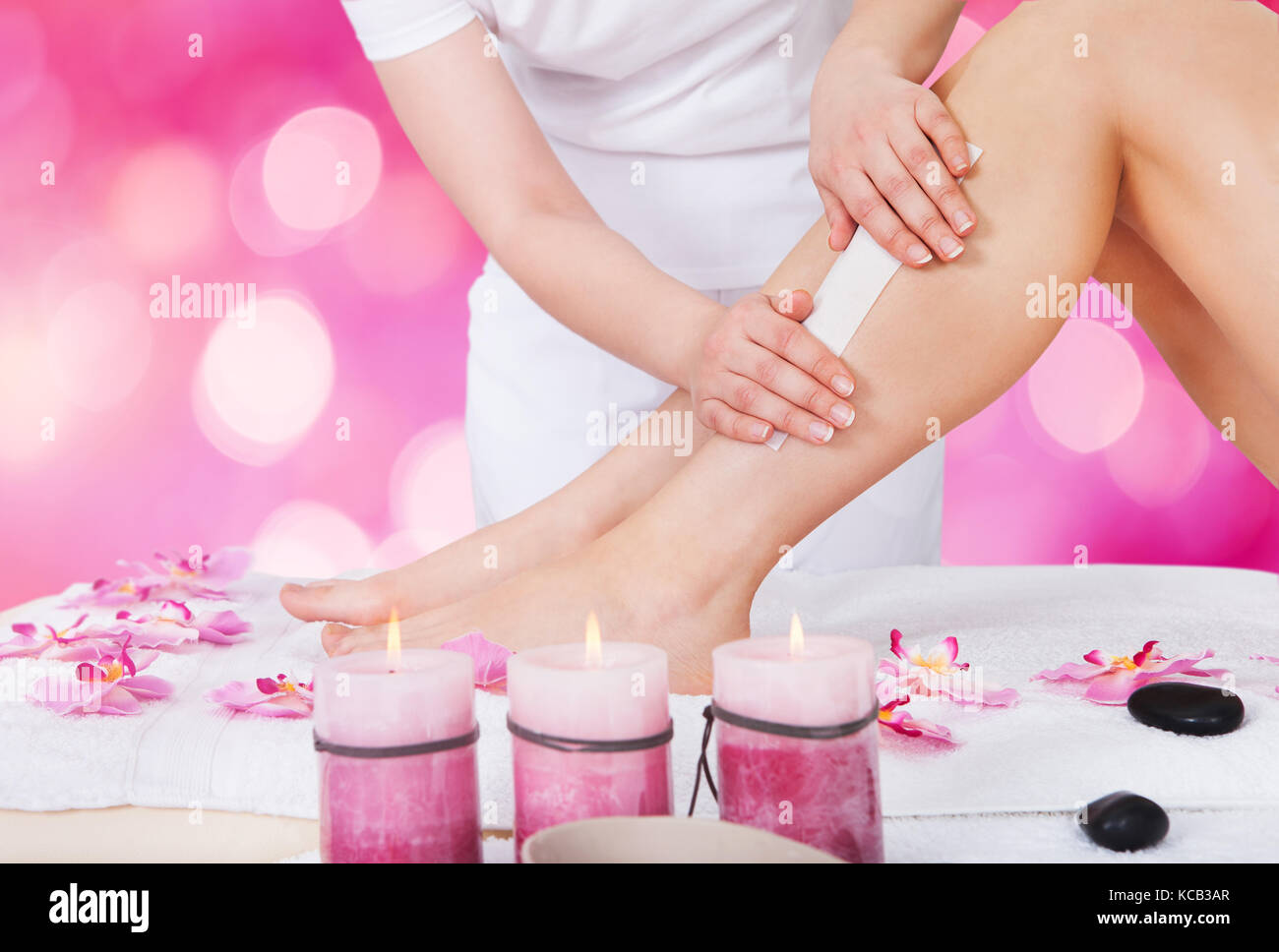 Close-up di una estetista ceretta donna gamba con striscia di cera a beauty spa Foto Stock