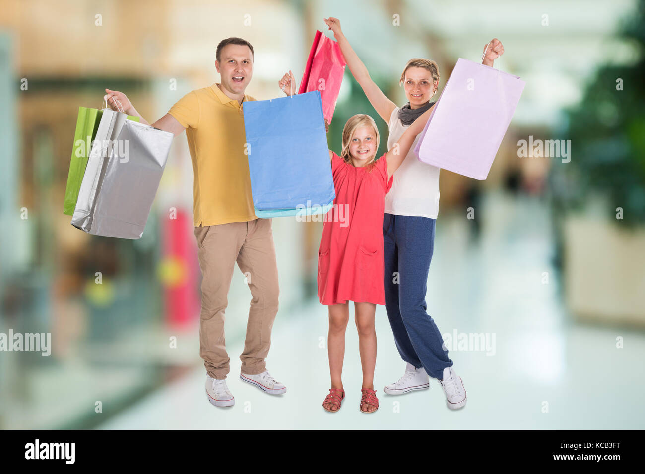 Ritratto di una famiglia felice con le borse della spesa in piedi al Centro Commerciale per lo Shopping Foto Stock