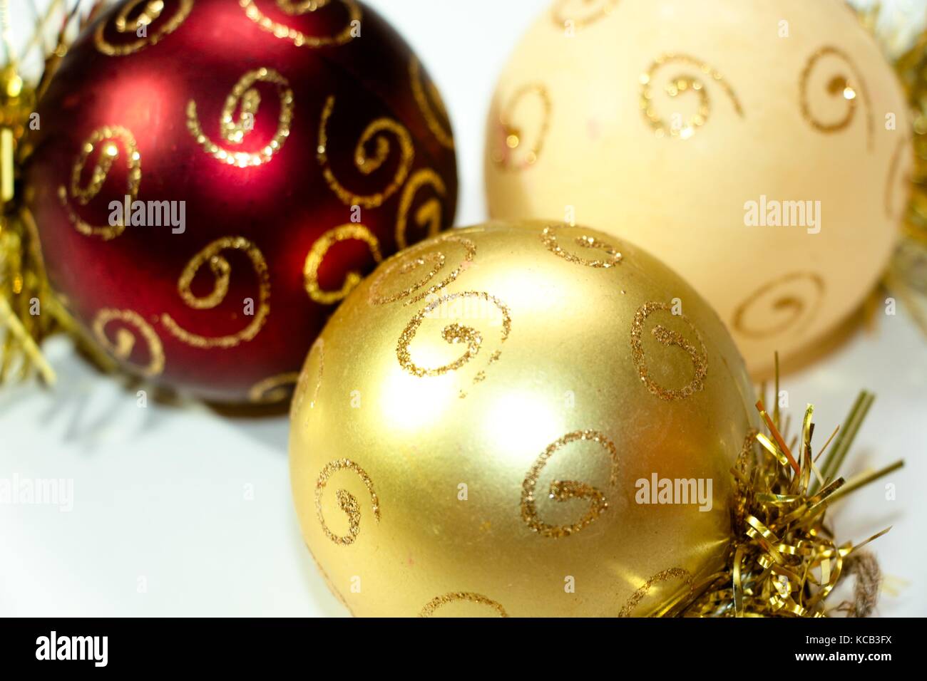 Tre multi-colore di decorazioni di Natale a forma di palloncino, dipinti con motivi color oro. Una composizione del nuovo anno di giocattoli su un bianco backgroun Foto Stock