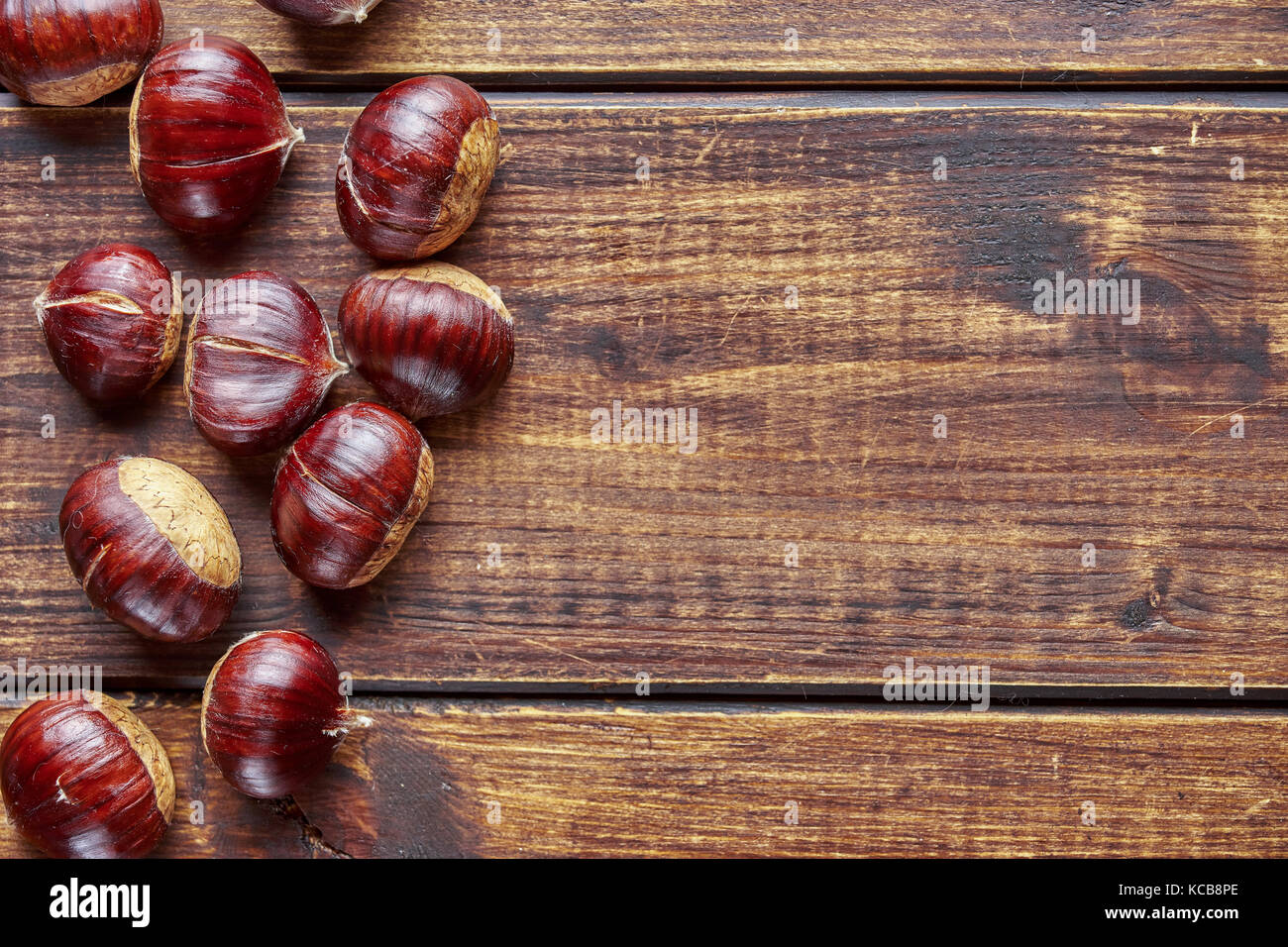 Vista dall'alto di castagne sulla scrivania di legno formando bordo sinistro per spazio di copia Foto Stock