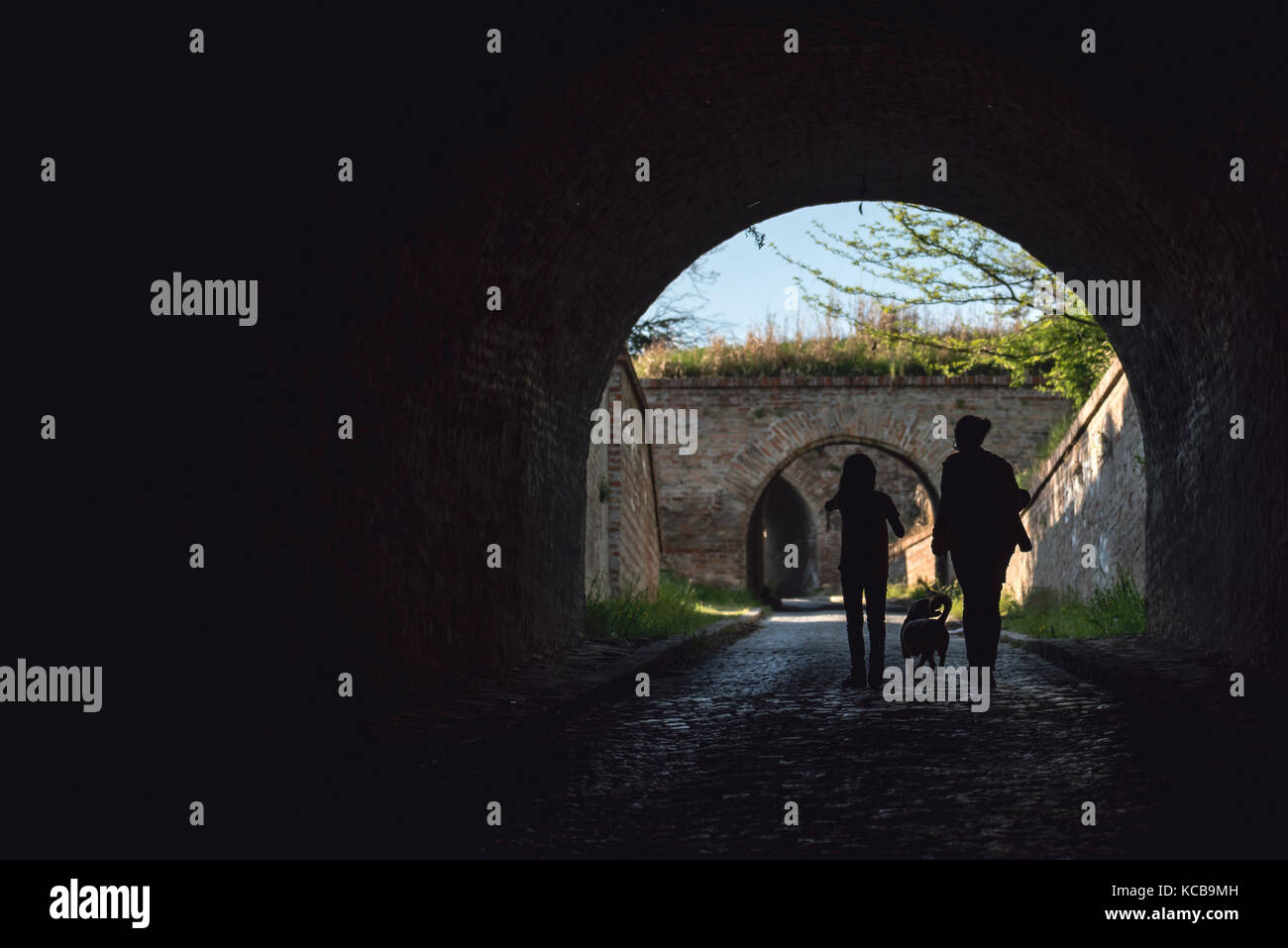 Madre e figlia camminando in un tunnel con un cane Foto Stock
