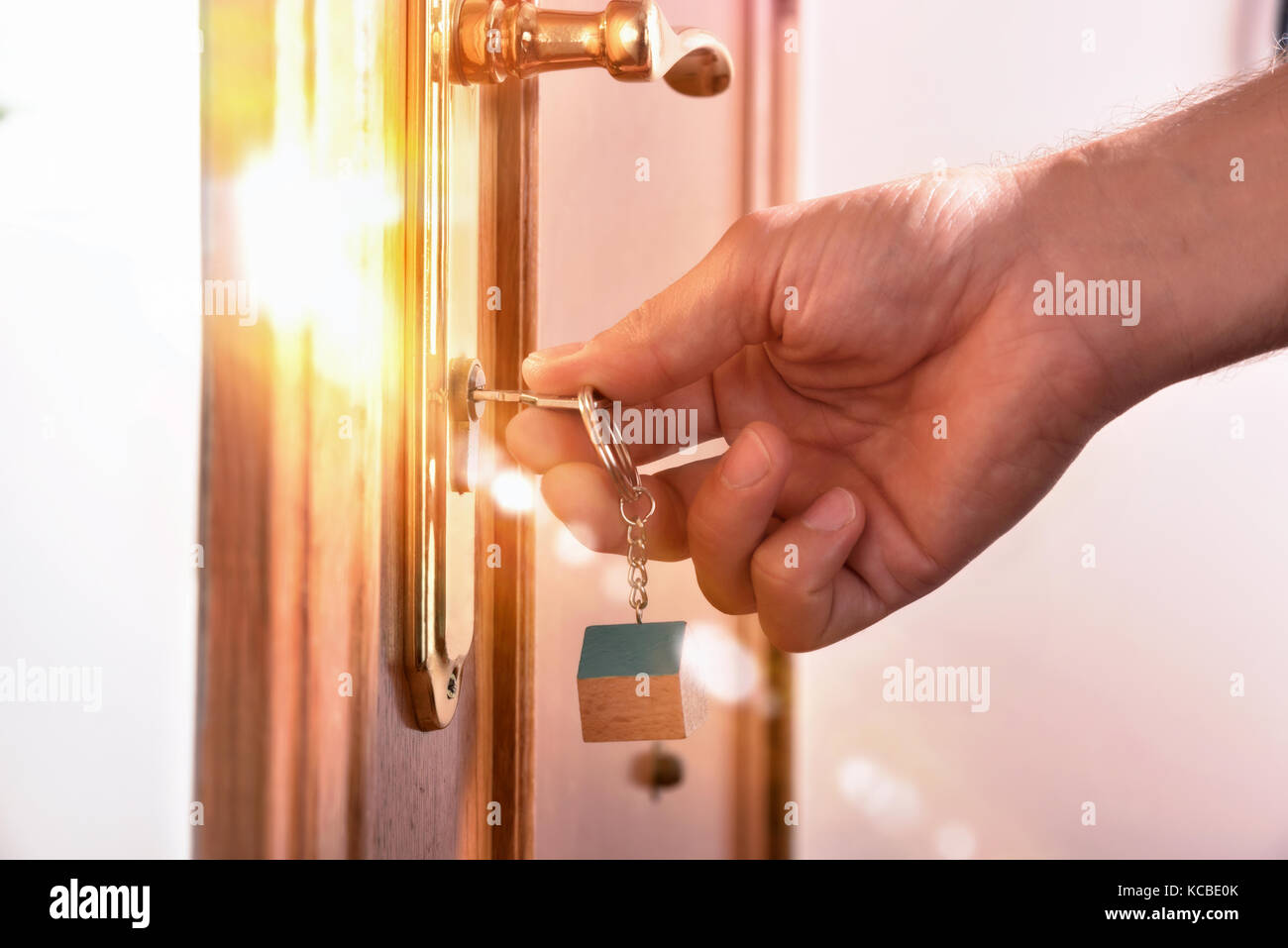 Ingresso di una casa con la mano che blocca la porta con luce dorata effetto. Vista laterale Foto Stock