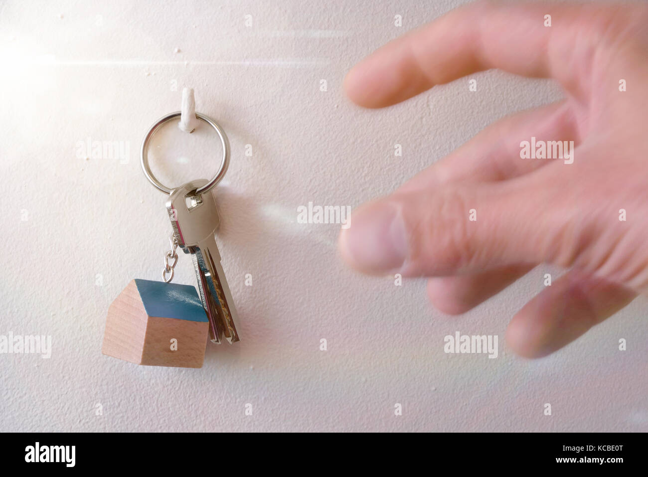 Mani che stanno andando a prendere le chiavi da una casa appeso ad un gancio nella parete Foto Stock