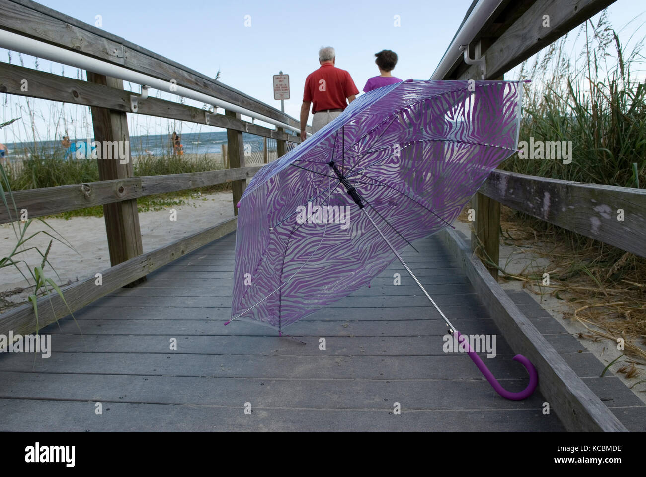 Caucasian Senior Couple (60-70 anni) a piedi lungo la passerella lontano da ombrello viola a Myrtle Beach SC, Stati Uniti. Foto Stock