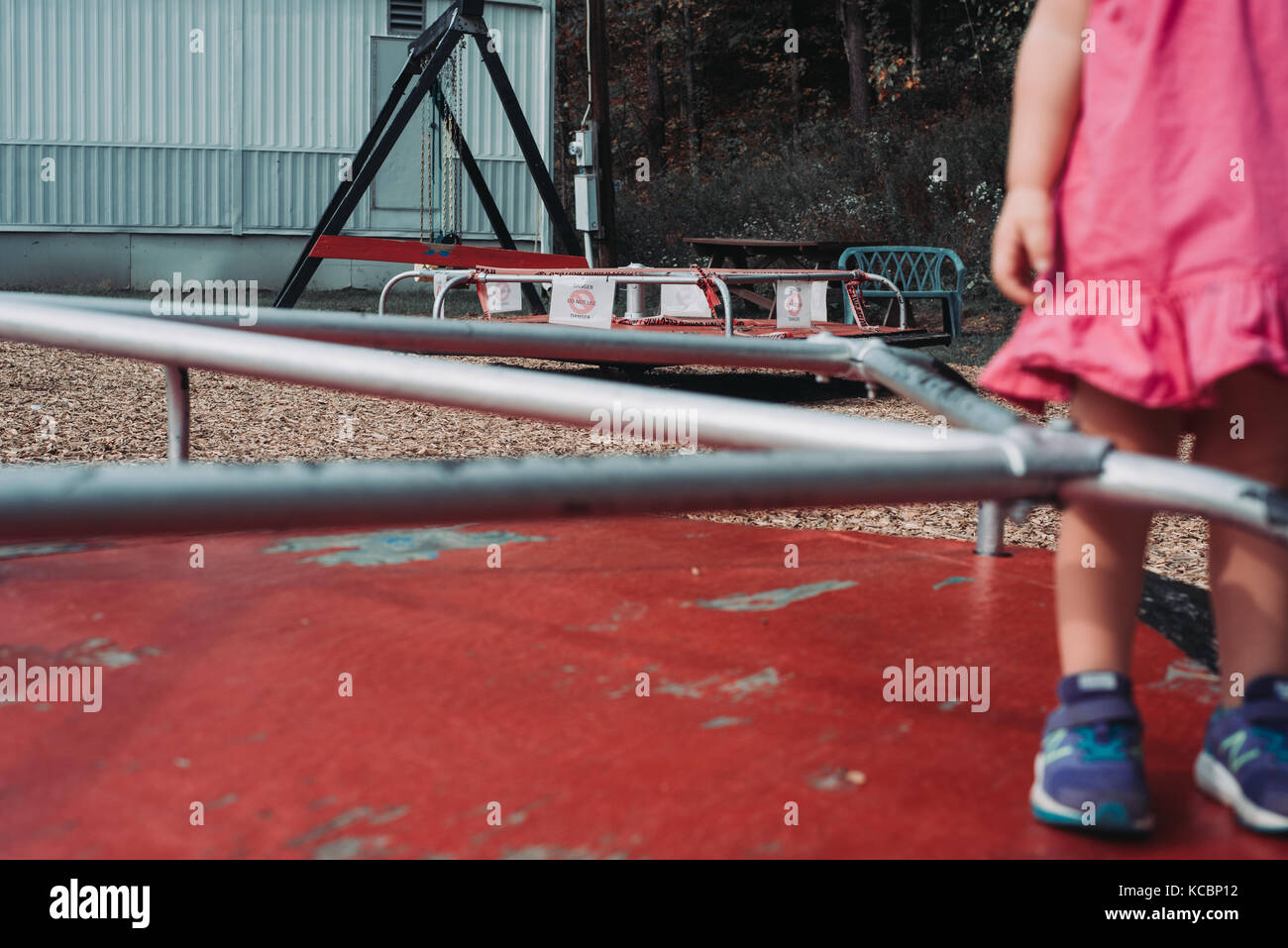 Un bambino sta in piedi su un giochino allegro in un parco giochi a basso reddito Foto Stock