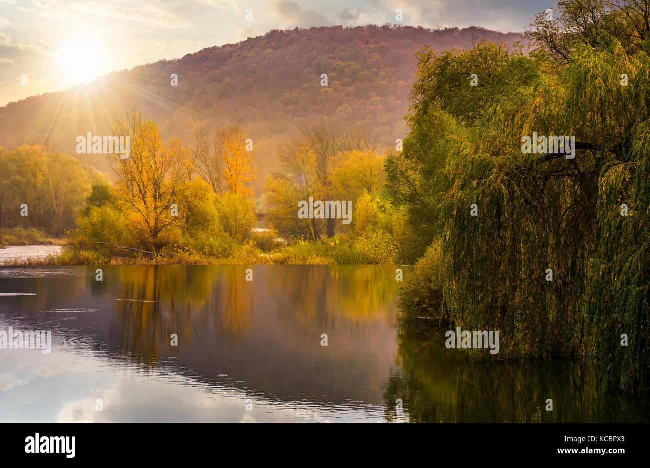 Paesaggio con fiume calmo in autunno al tramonto. bellissimo scenario di montagna con il rosso e il giallo fogliame Foto Stock