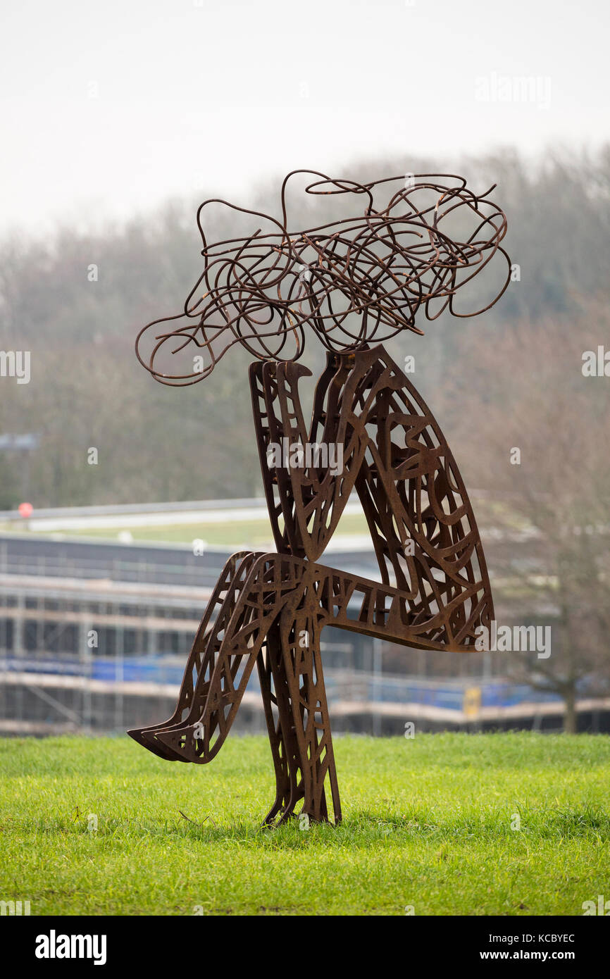 Outdoor scultura di metallo di stilizzati uomo seduto nel campo Foto Stock