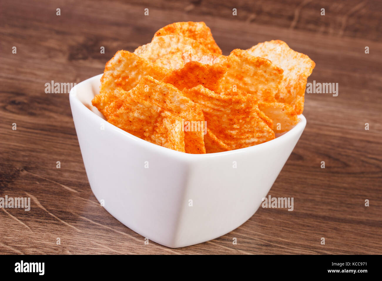 Cumulo di Croccanti patatine con peperoni in bianco ciotola sulla scheda rustico, la nozione di restrizione di mangiare alimenti dannosi per la salute Foto Stock Cumulo di Croccanti patatine con peperoni in bianco ciotola sulla scheda rustico, la nozione di restrizione di mangiare alimenti dannosi per la salute Foto Stock