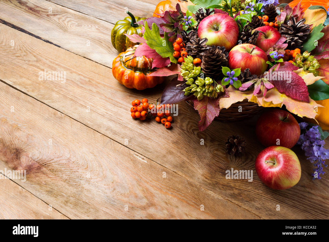 Ringraziamento o il messaggio di saluto di caduta con mele, rowan bacche, verde sementi, coni, fiori blu sullo sfondo di legno, spazio di copia Foto Stock