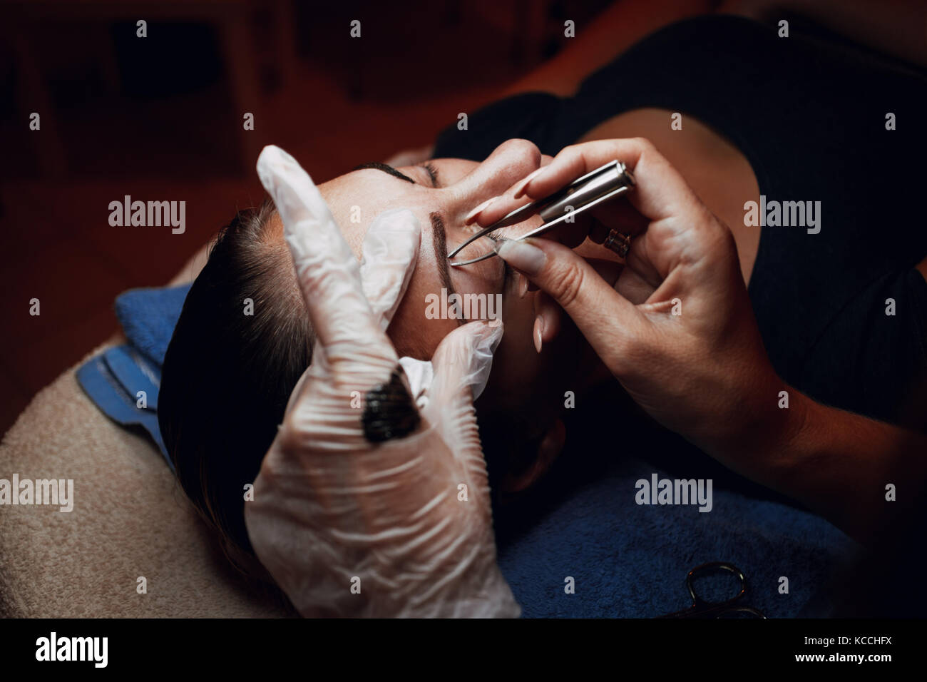 Primo piano di una estetista mani applicazione permanente di make-up per le sopracciglia al modello. Foto Stock
