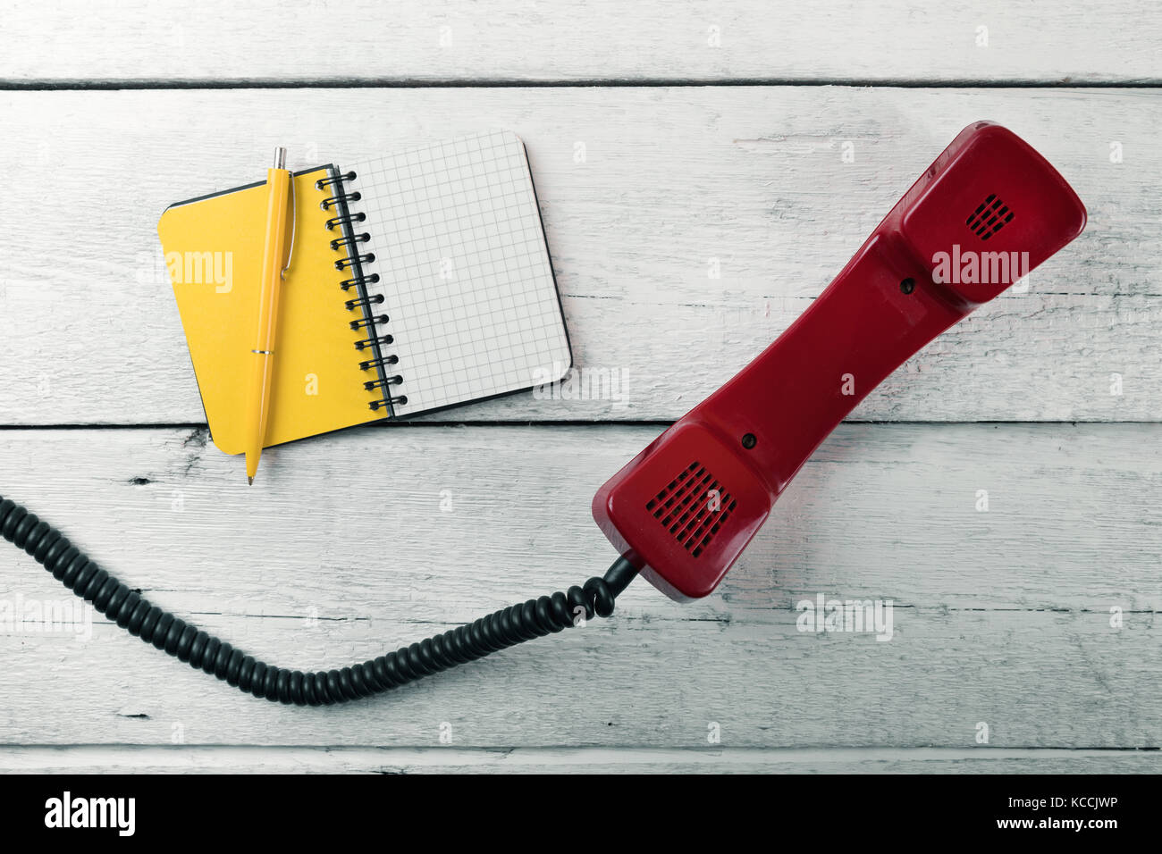 Il ricevitore del telefono e vuoto sul notebook bianco tavola di legno Foto Stock