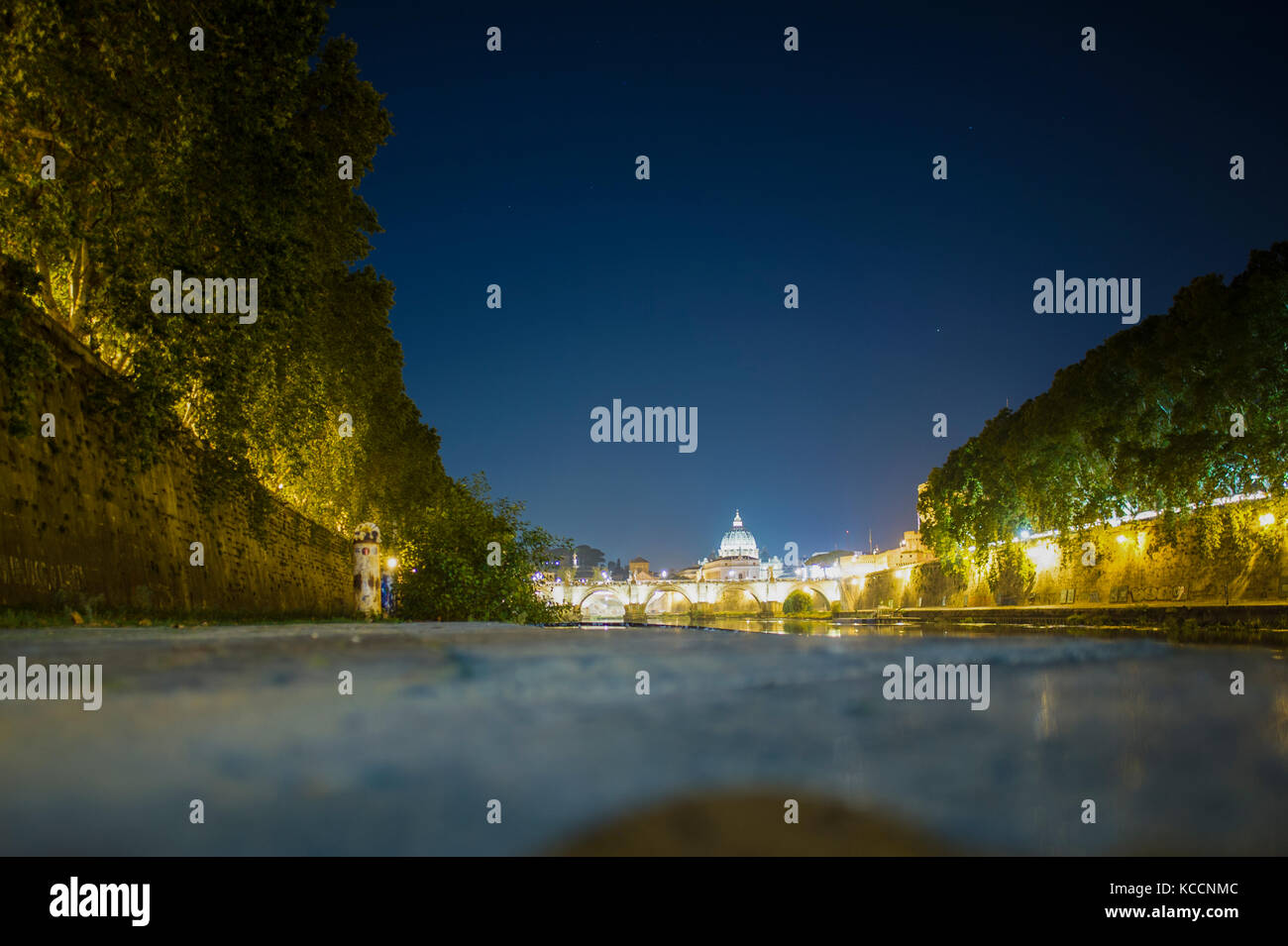 (Fuoco selettivo) Tenebrologo della Basilica di San Pietro. Foto scattata sulle rive del fiume Tevere con il terreno in primo piano Foto Stock