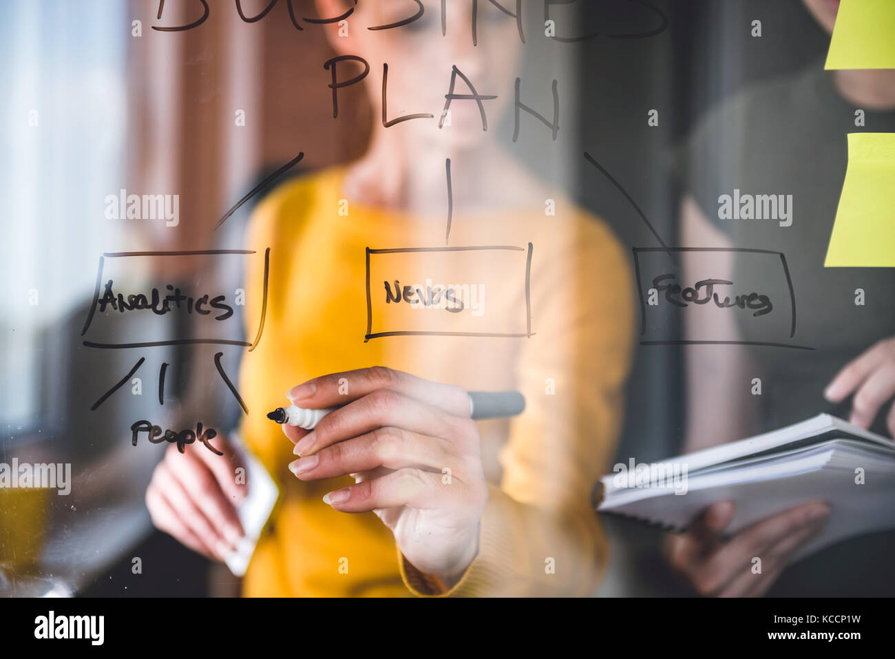 La donna la scrittura di note sulla scheda di vetro presso l'ufficio Foto Stock