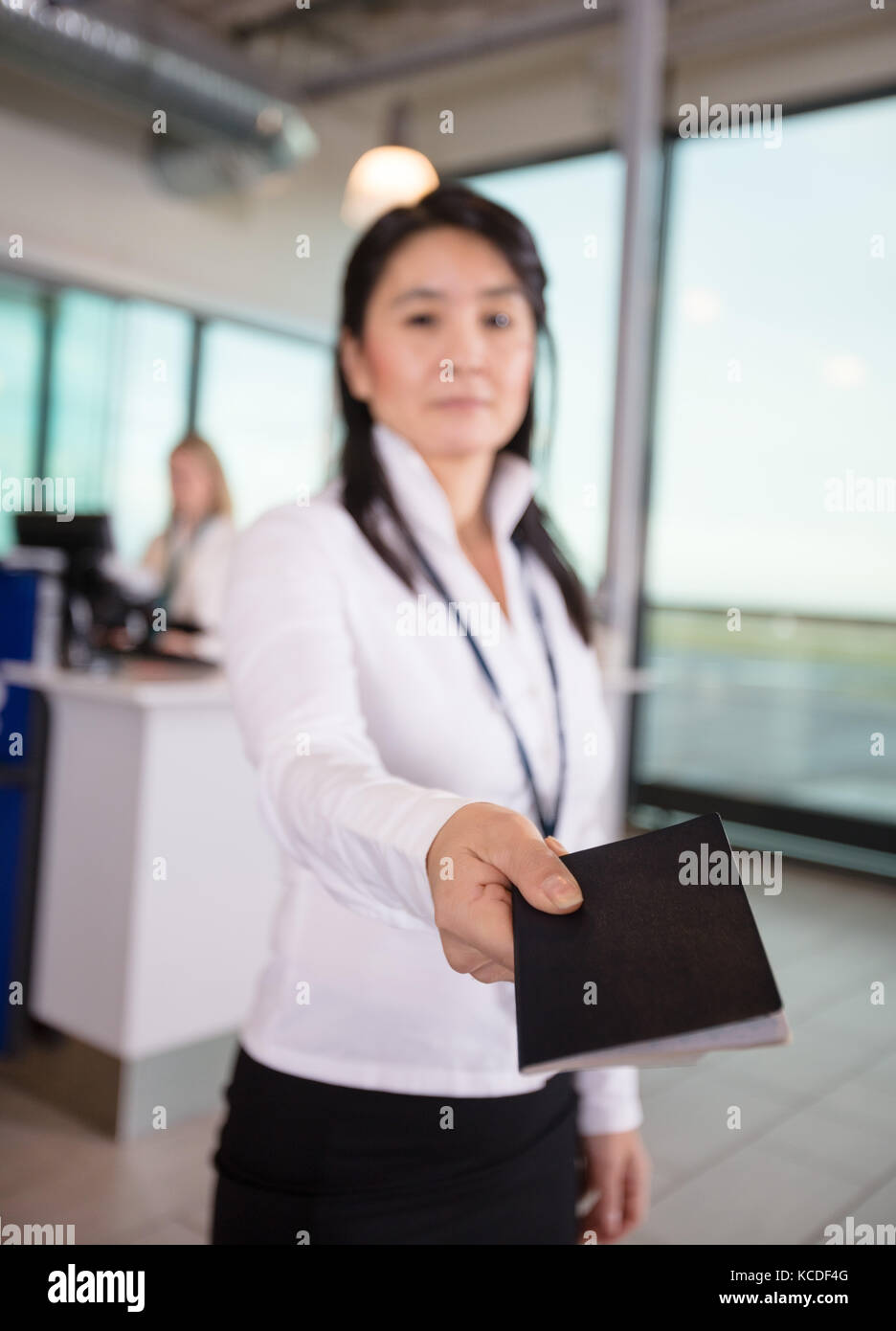 Metà femmina adulta membro dello staff dando il passaporto al terminal aeroportuale Foto Stock