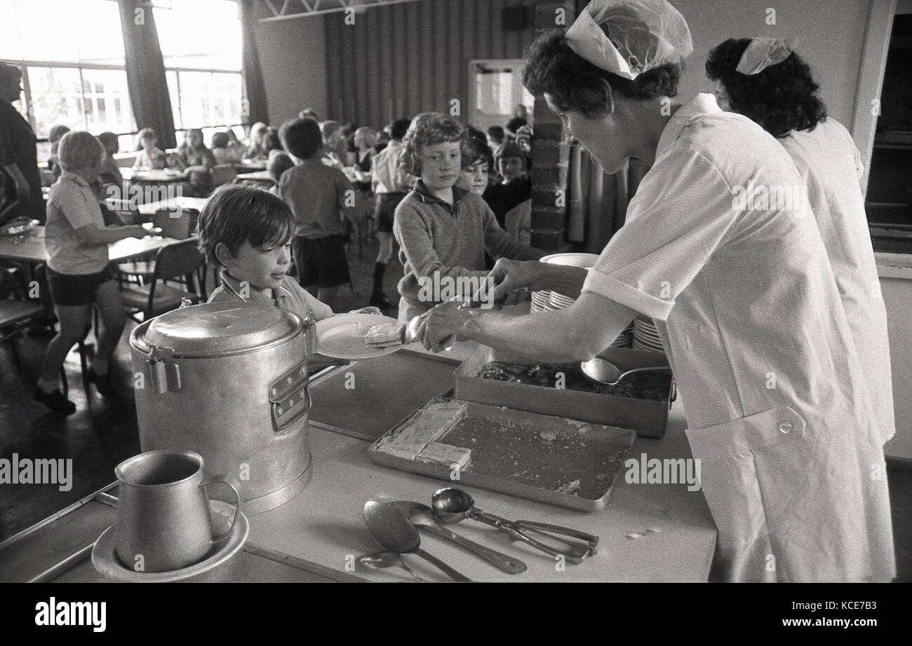 Anni Settanta, storico, scuola cena onorevoli colleghe che serve cibo per bambini a pranzo, Langbourne scuola primaria, Dulwich, London, SE21, Inghilterra, Regno Unito. Foto Stock