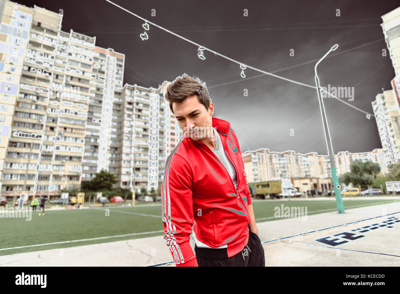 Giovane uomo in un rosso tuta sportiva contro lo sfondo di una città Foto Stock