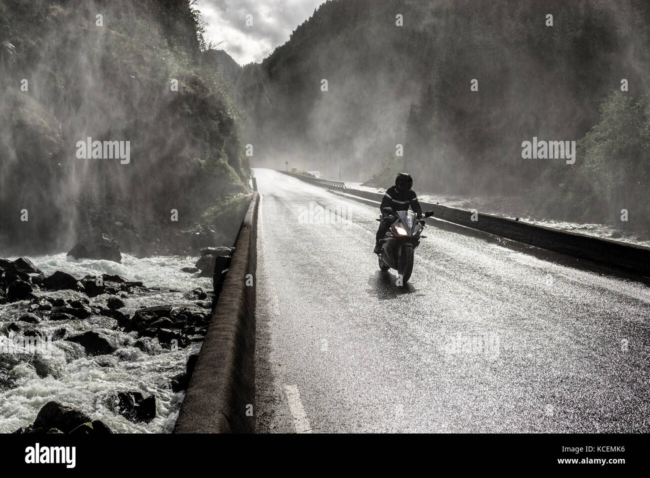 Moto veloce di guida sul bagnato canyon valley road e il ponte sul fiume. Foto Stock