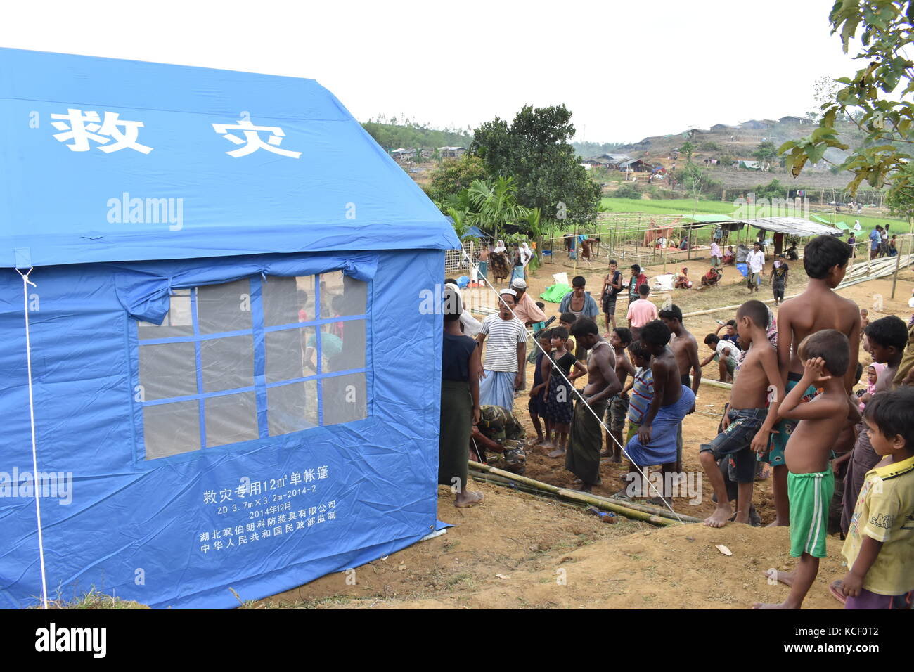 (171004) -- DACCA, 4 ottobre 2017 (Xinhua) -- un personale dell'esercito aiuta una famiglia Rohingya a creare una tenda di soccorso cinese in un campo nel distretto di Cox's Bazaar, Bangladesh, il 3 ottobre 2017. La Cina ha recentemente inviato rifornimenti per i rifugiati rohingya in Bangladesh. (Xinhua/Jibon Ahsan) (zcc) Foto Stock