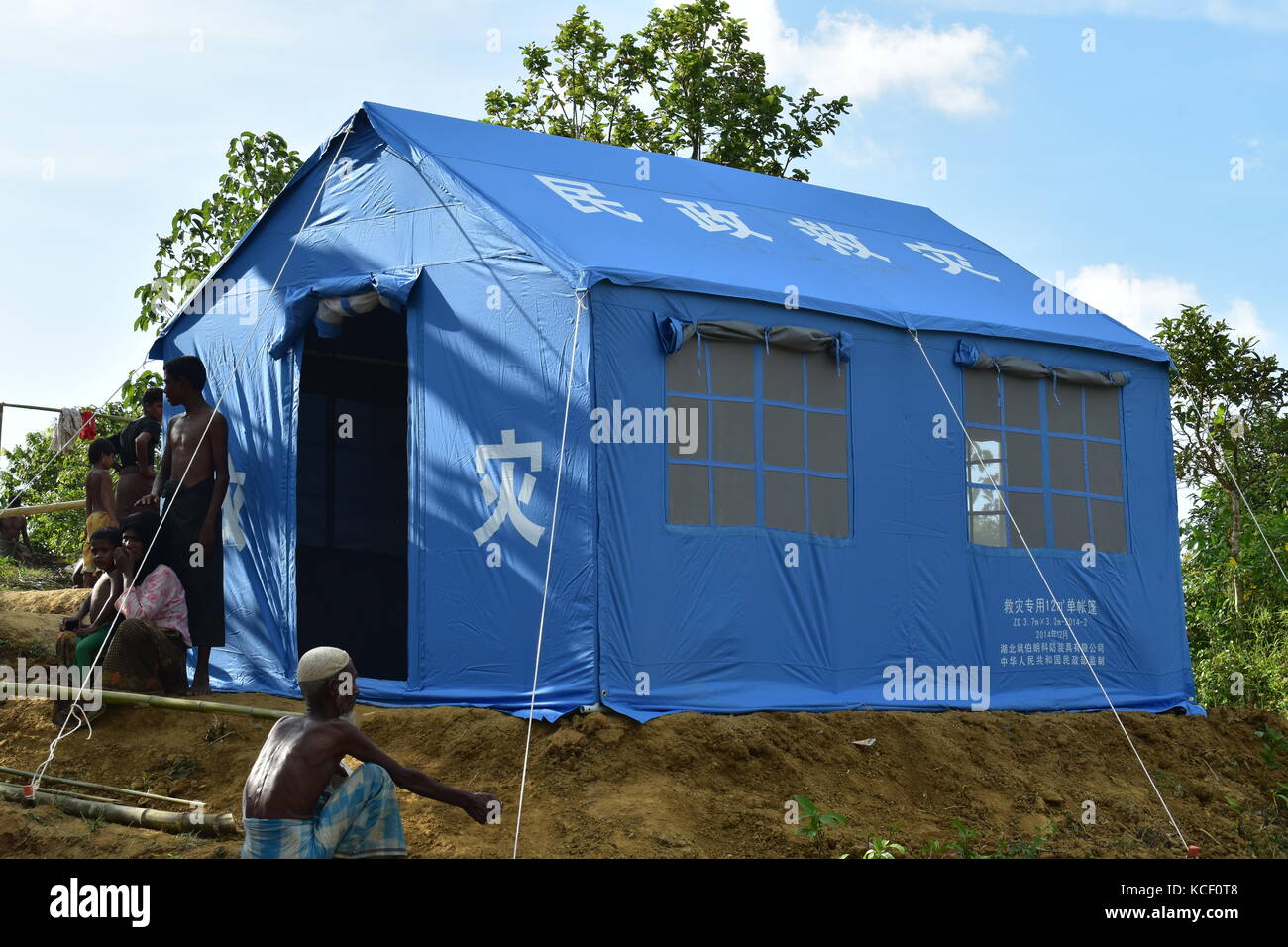 (171004) -- DACCA, 4 ottobre 2017 (Xinhua) -- le persone riposano vicino a una tenda di soccorso cinese in un campo nel distretto di Cox's Bazaar, Bangladesh, il 3 ottobre 2017. La Cina ha recentemente inviato rifornimenti per i rifugiati rohingya in Bangladesh. (Xinhua/Jibon Ahsan) (zcc) Foto Stock