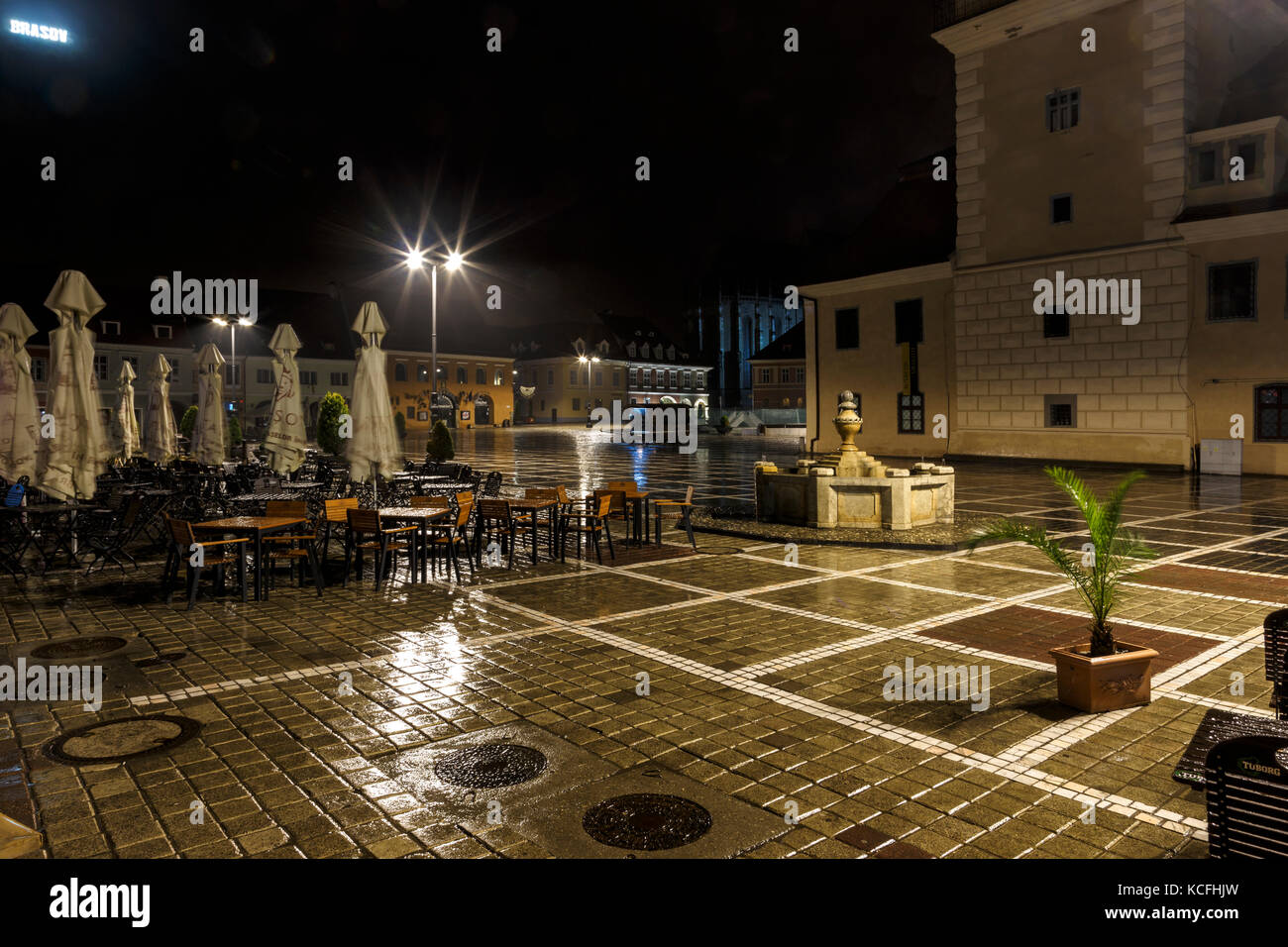 La piazza del consiglio durante la pioggia in Brasov, Romania. vista con famosi palazzi di sera e luci di pubblico. Foto Stock