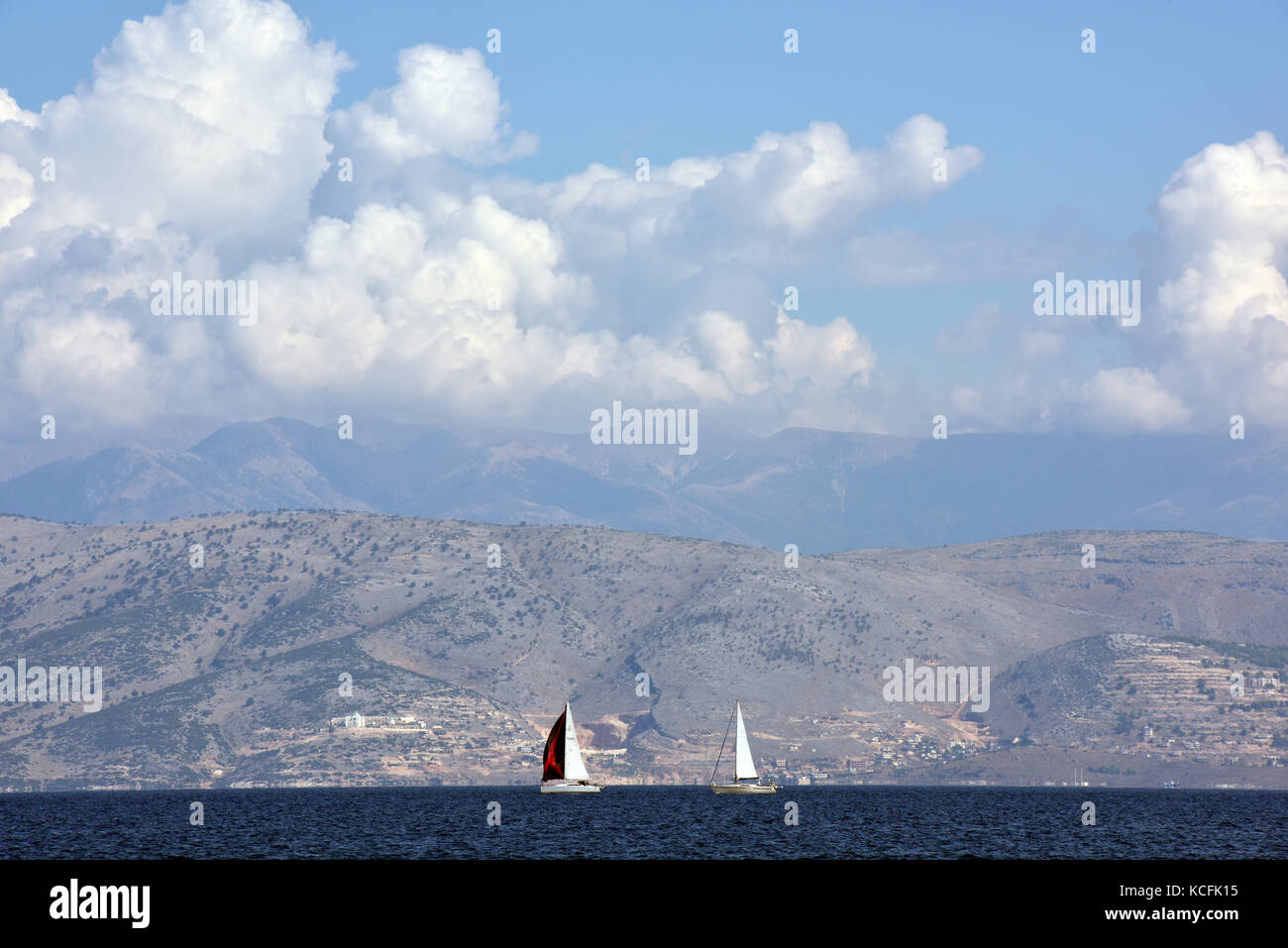 Due barche barca a vela della costa di Corfu con le montagne albanesi in background. Foto Stock