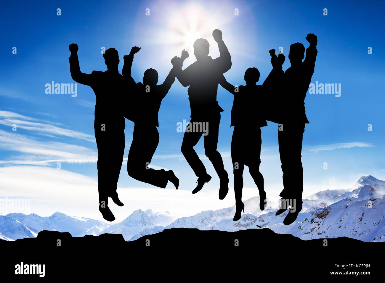 Silhouette di Persone che saltano contro le montagne nevose Foto Stock