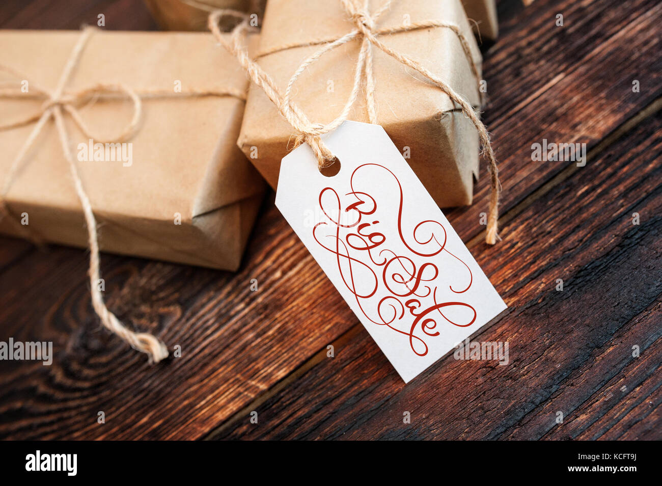 Due confezioni regalo e tag con grande vendita testo su carta kraft e sfondo di legno. scritto a mano la calligrafia e scritte Foto Stock
