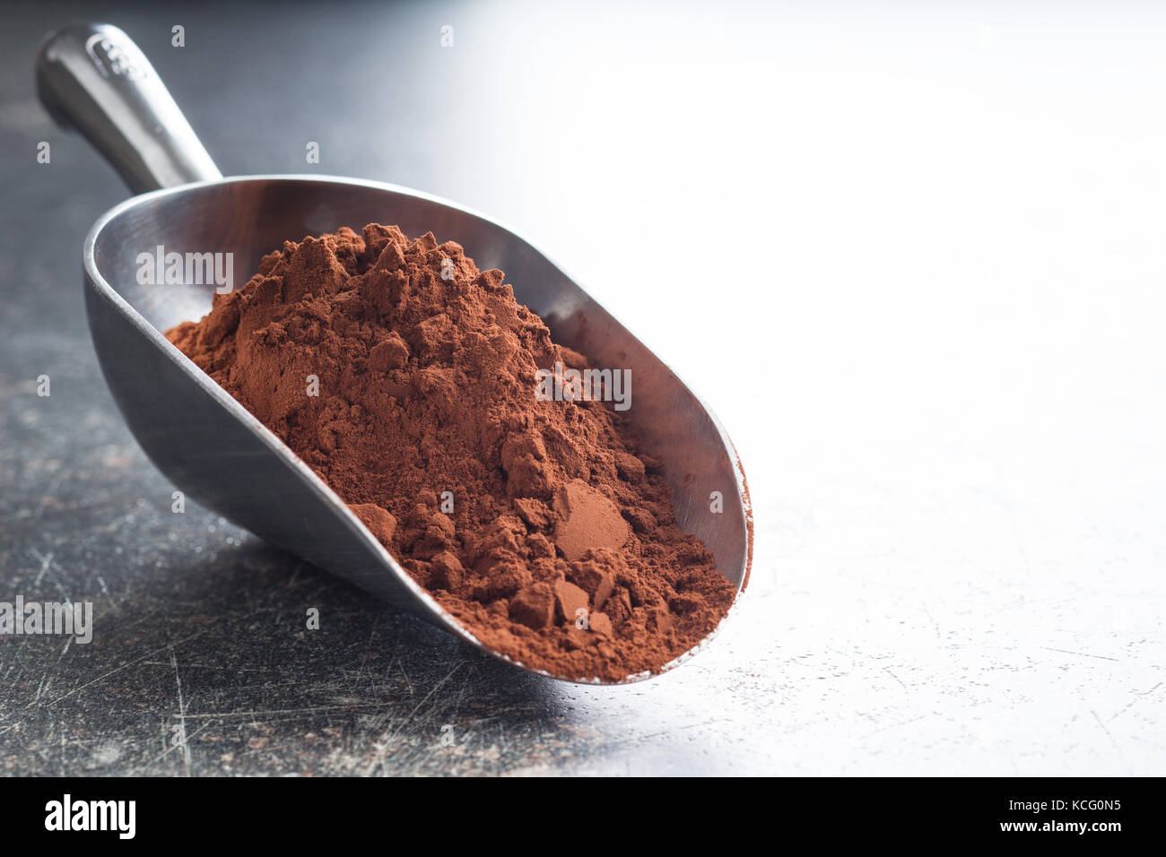 Gustoso cacao in polvere nel convogliatore sul vecchio tavolo da cucina. brown cacao. Foto Stock