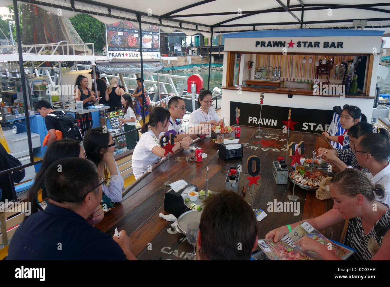 Diners a stella di gamberi, i pescherecci con reti da traino convertito in un ristorante di pesce nel Marina, Cairns, Queensland, Australia. No signor o PR Foto Stock