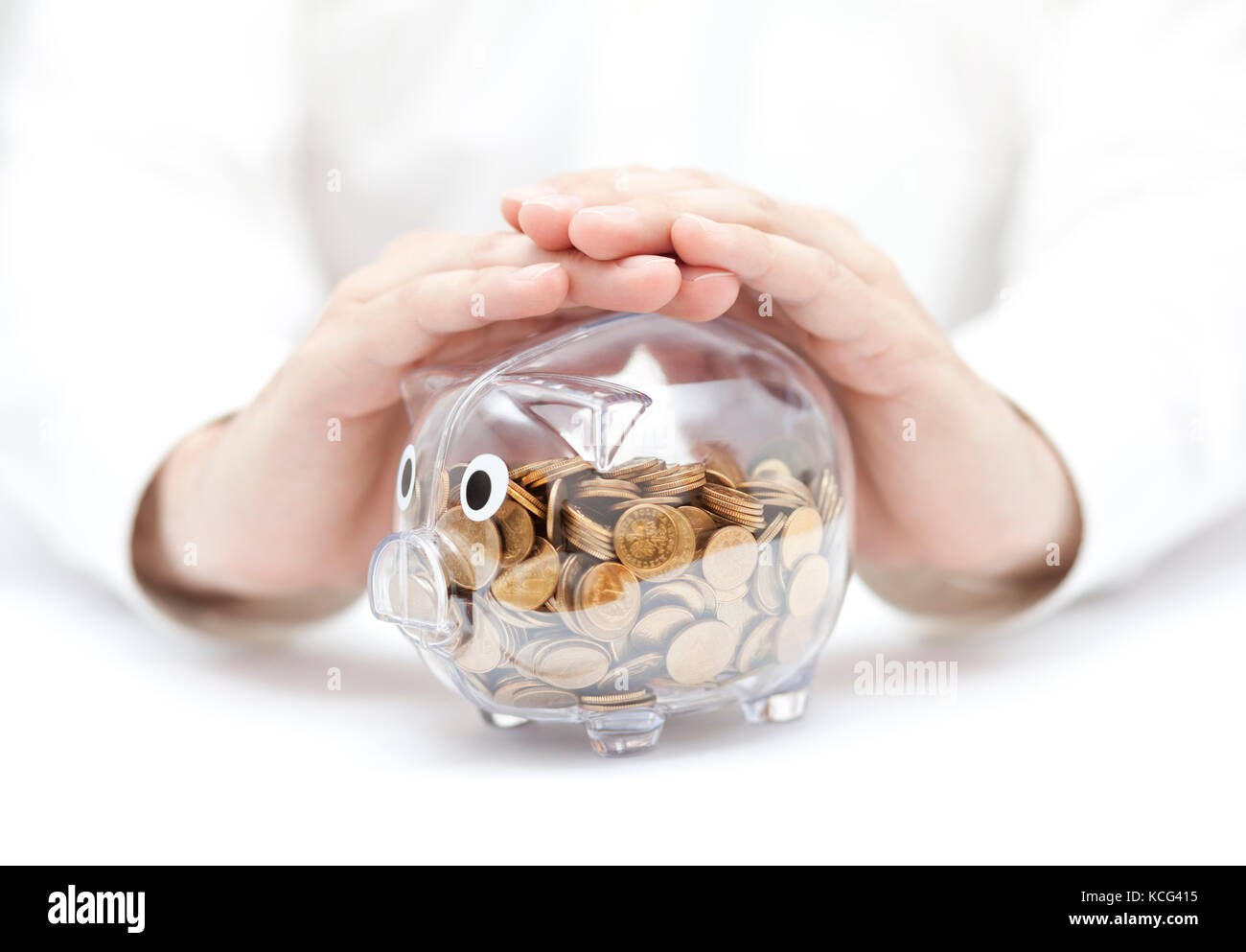 Proteggere il tuo denaro trasparente salvadanaio con monete coperti da mani. Foto Stock