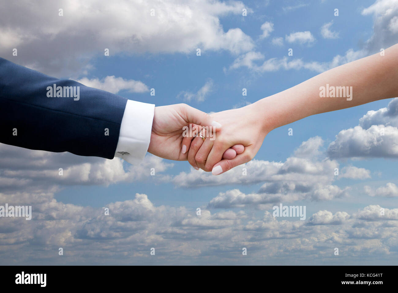 Sposi tenendo le mani sul cielo blu con nuvole Foto Stock