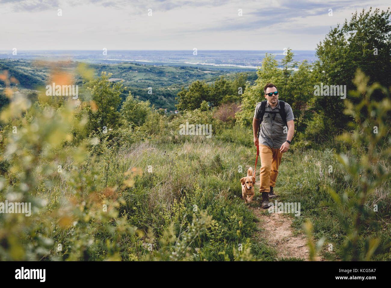 Uomo con un cane a piedi lungo un sentiero escursionistico sulla montagna Foto Stock