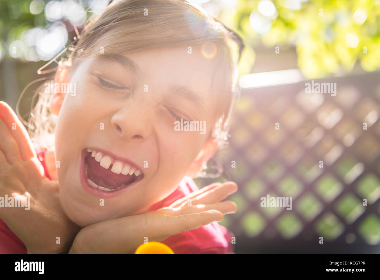 Piccolo felice ragazza sorridente e tenendo le mani al di sotto del mento Foto Stock