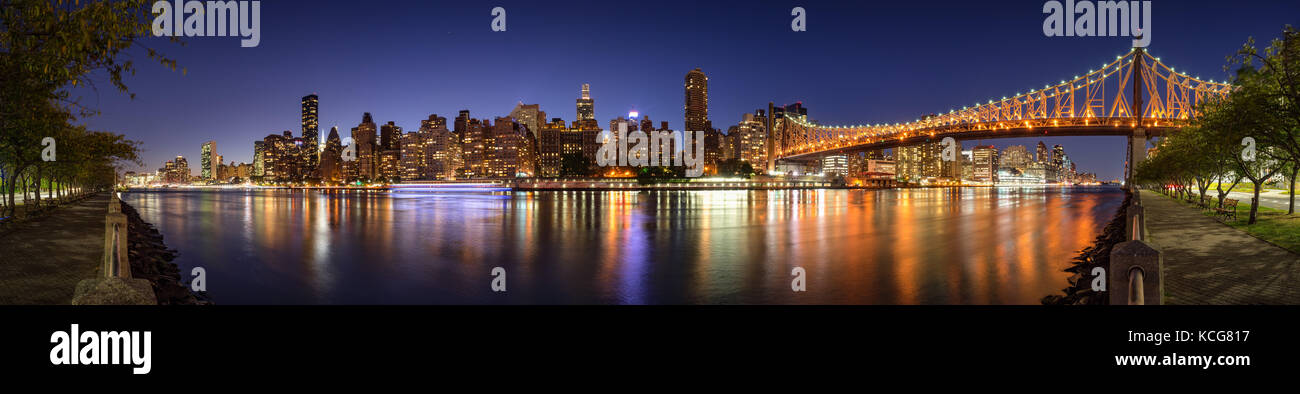 Panoramica vista serale di Manhattan Midtown East di Roosevelt Island con la illumina il Queensboro Bridge. La città di New York Foto Stock