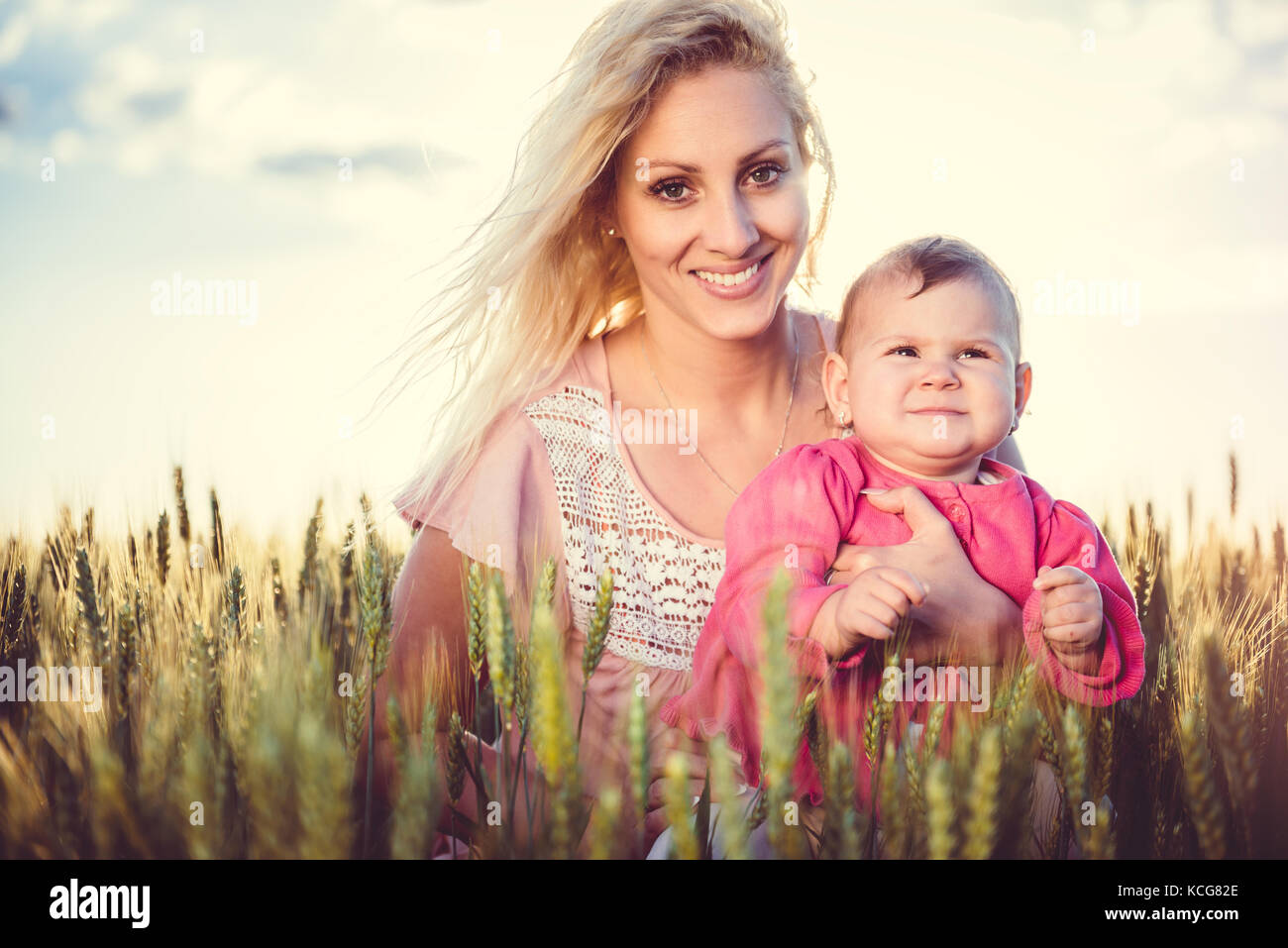 Felice madre tenendo la sua bambina le braccia nel campo di grano Foto Stock