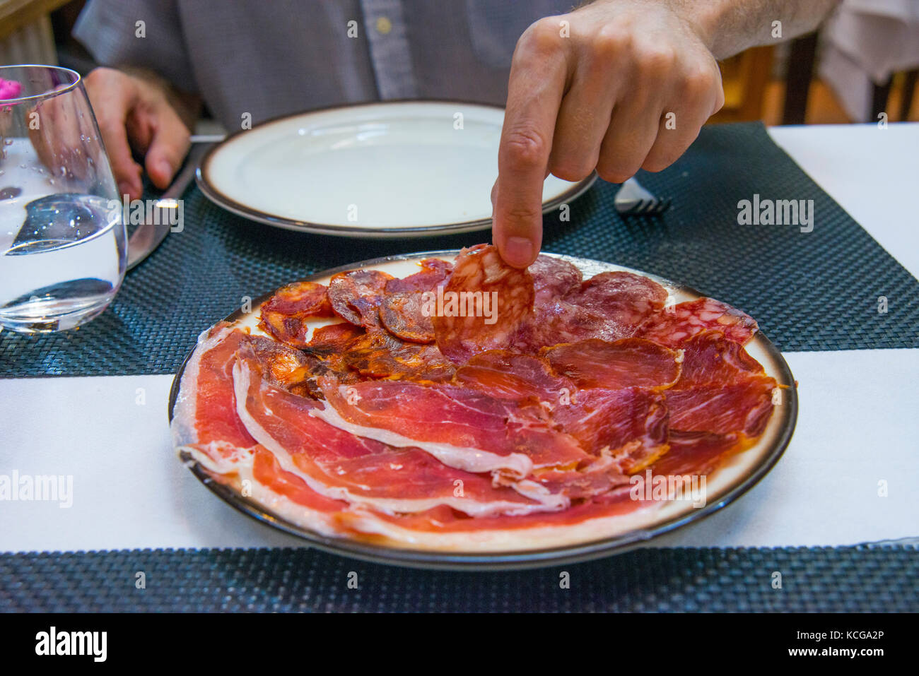 Mano d'uomo avente il chorizo iberico in un ristorante. Salamanca, Spagna. Foto Stock